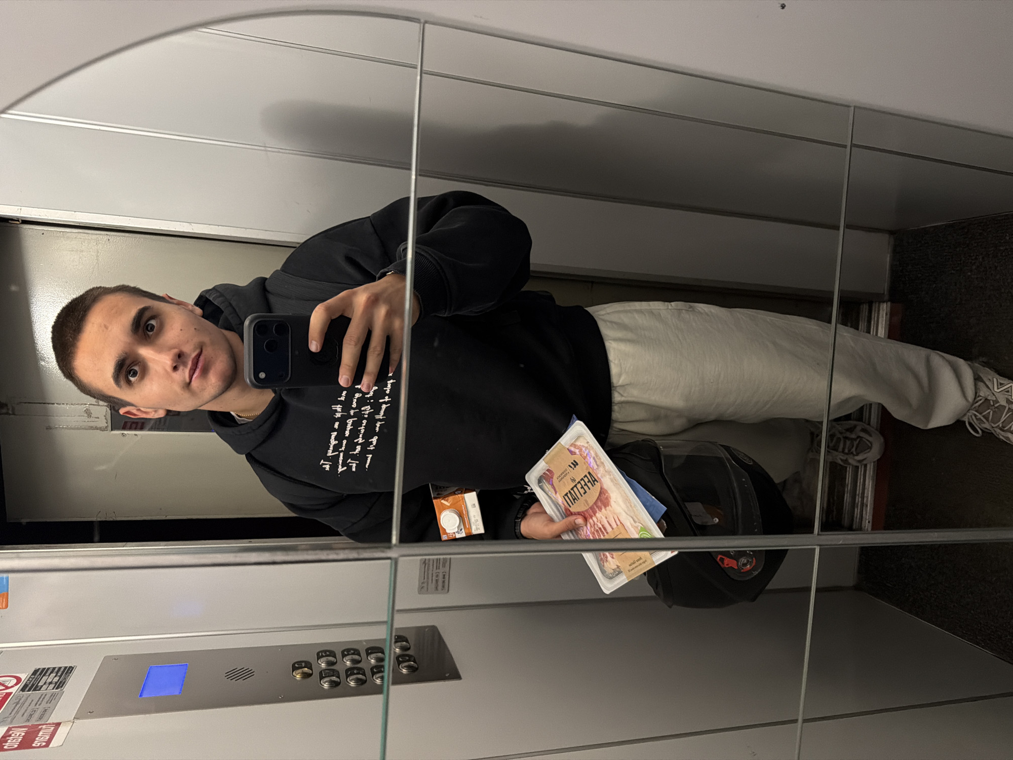 Man takes elevator selfie while holding bacon package in Milan