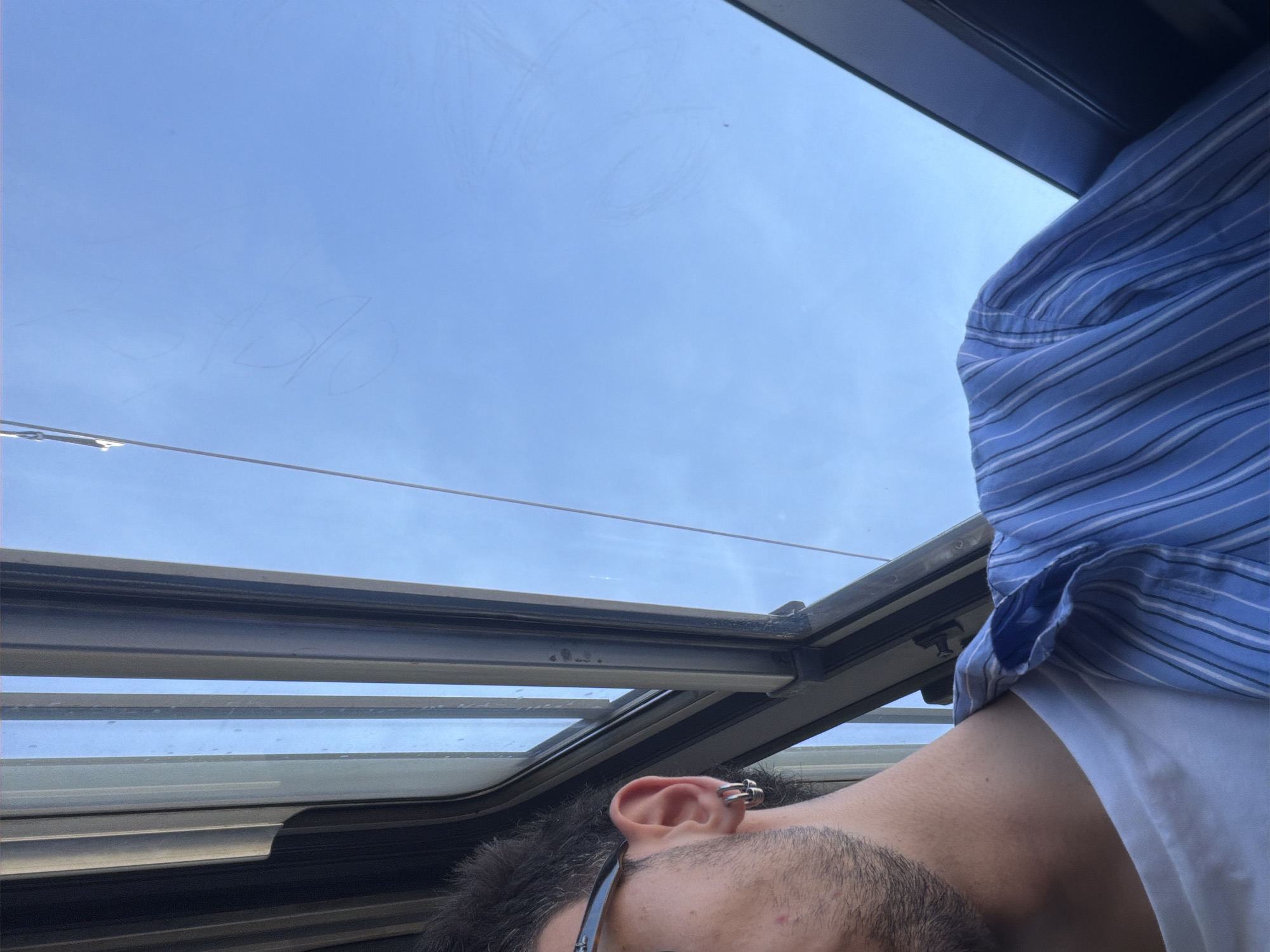 Person gazes at sky through sunroof in Milan