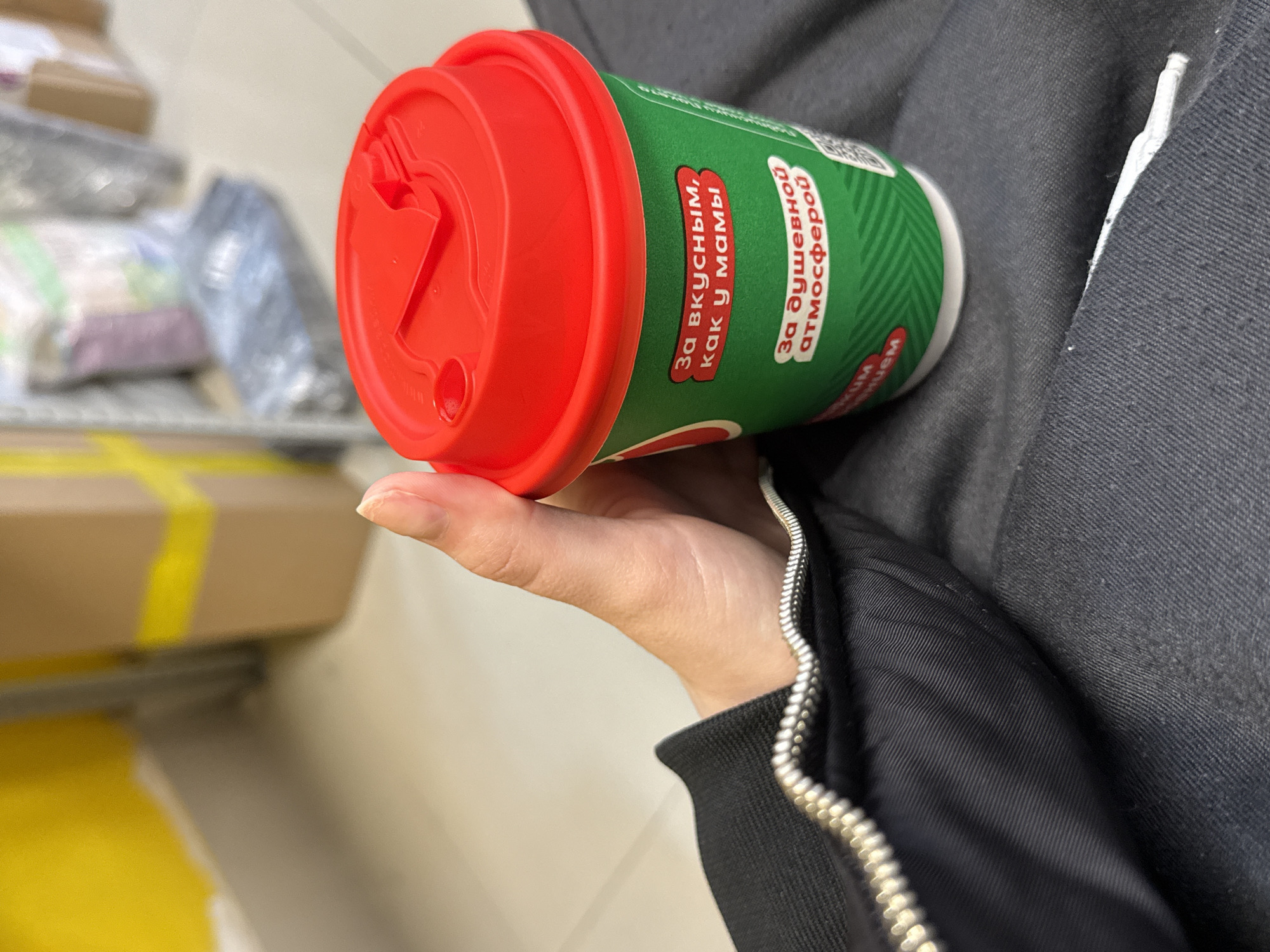 Person with Russian-text coffee cup observed indoors