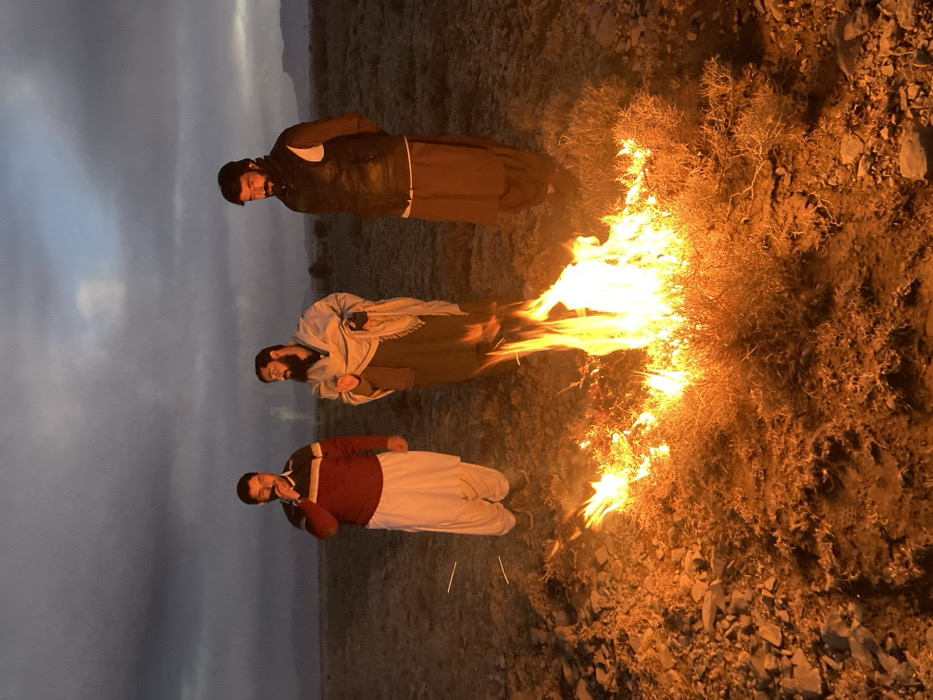 Three men gather around bonfire in rural Pakistan
