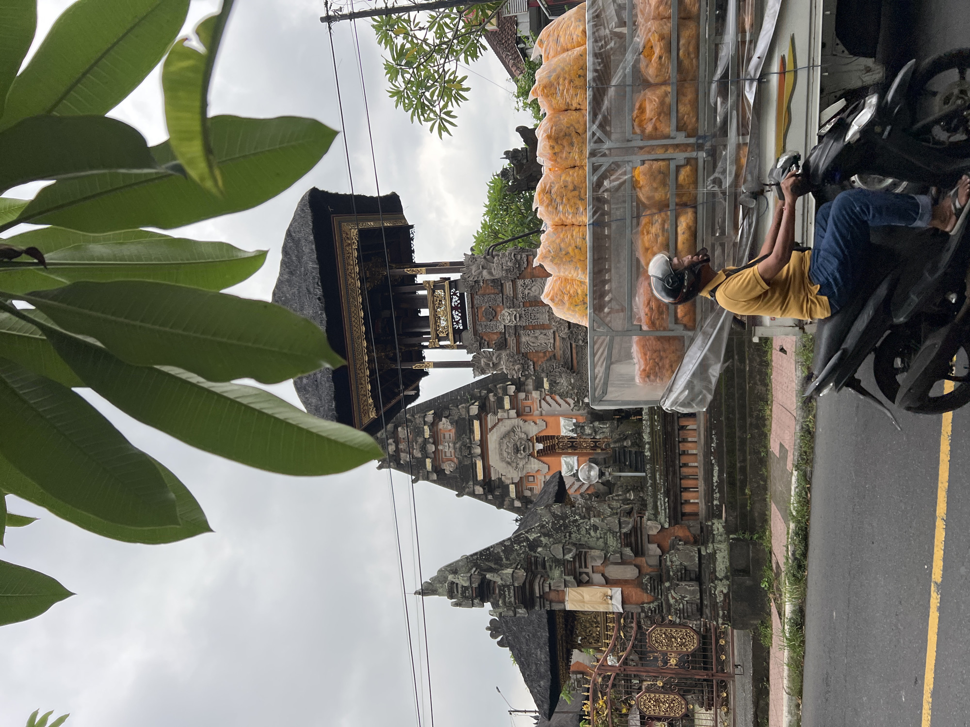 Artisan works metal craft amid bustling Ubud street scene