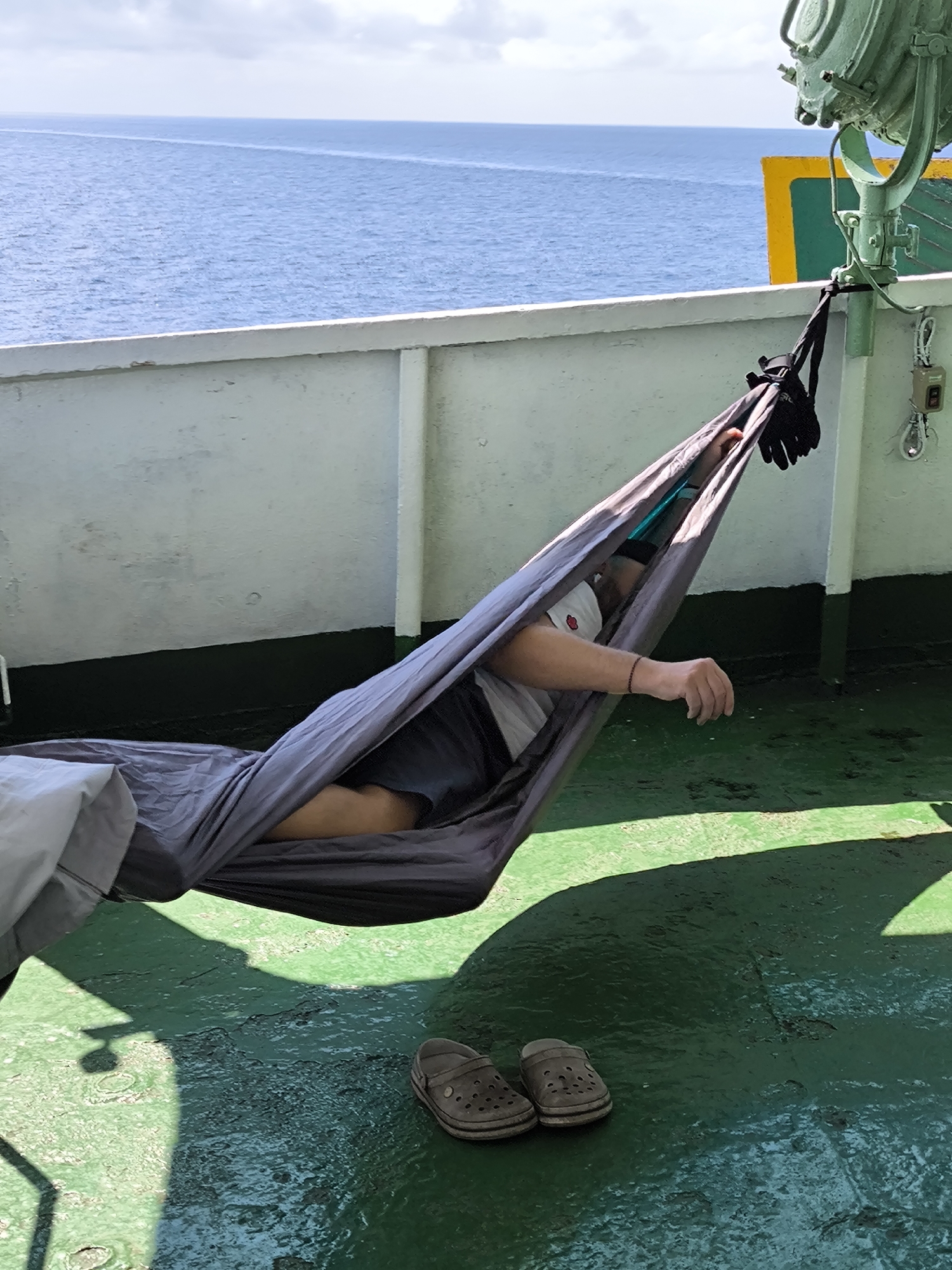 Passenger rests in hammock on vessel deck in Indonesia