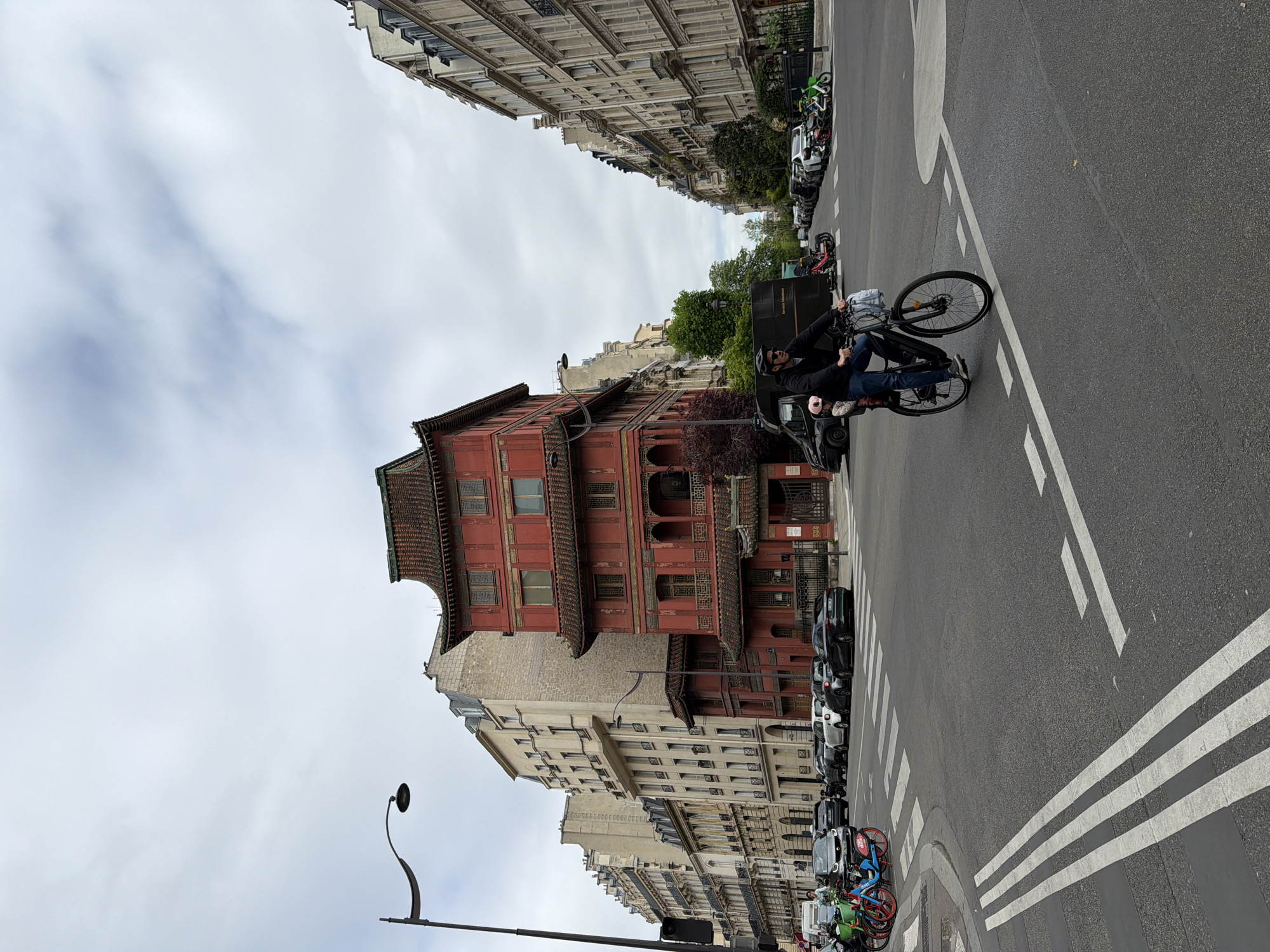 Cyclist crosses street near Chinese pagoda in Paris