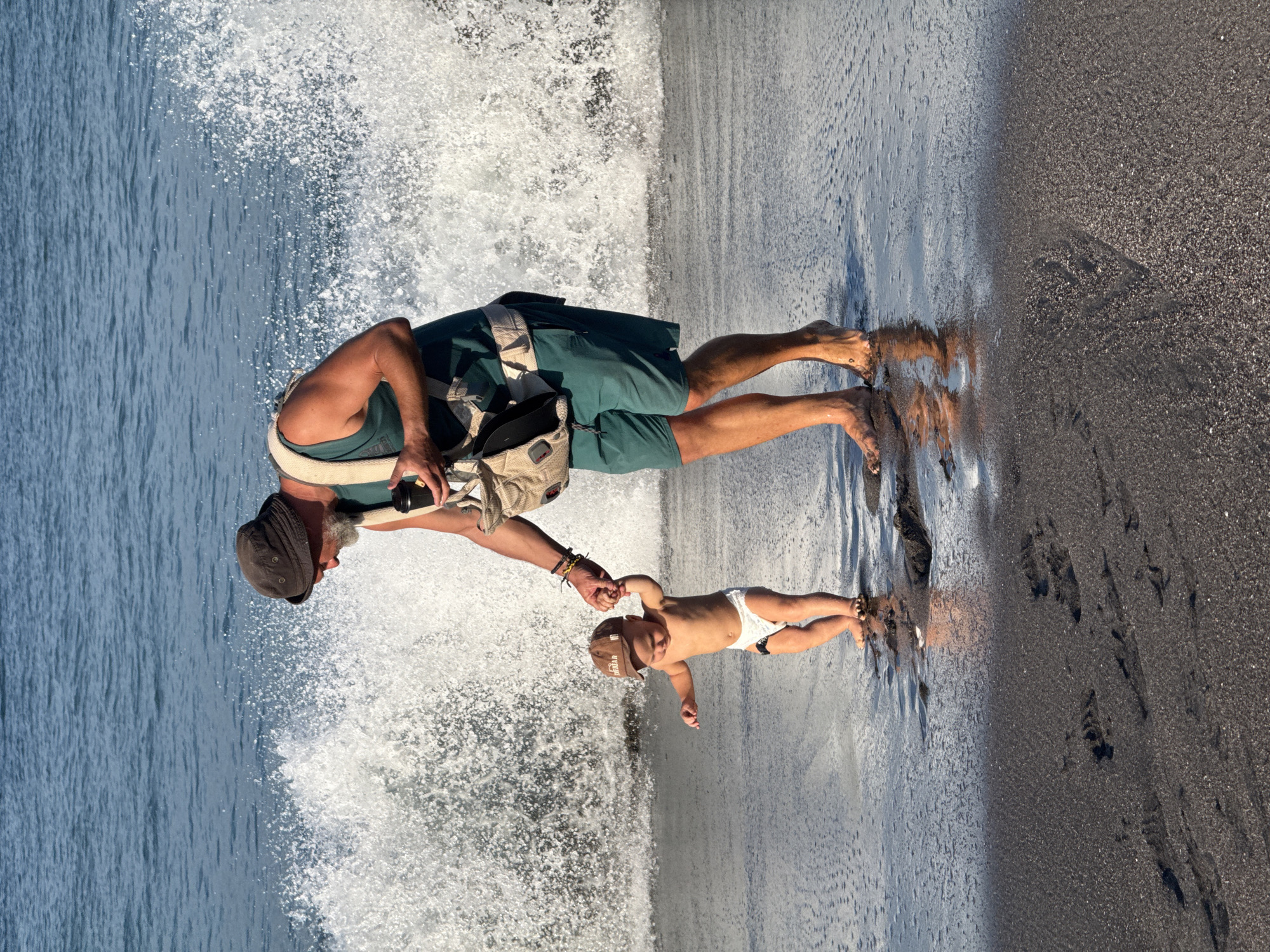 Man carries baby in shallow waters near Mengwi beach