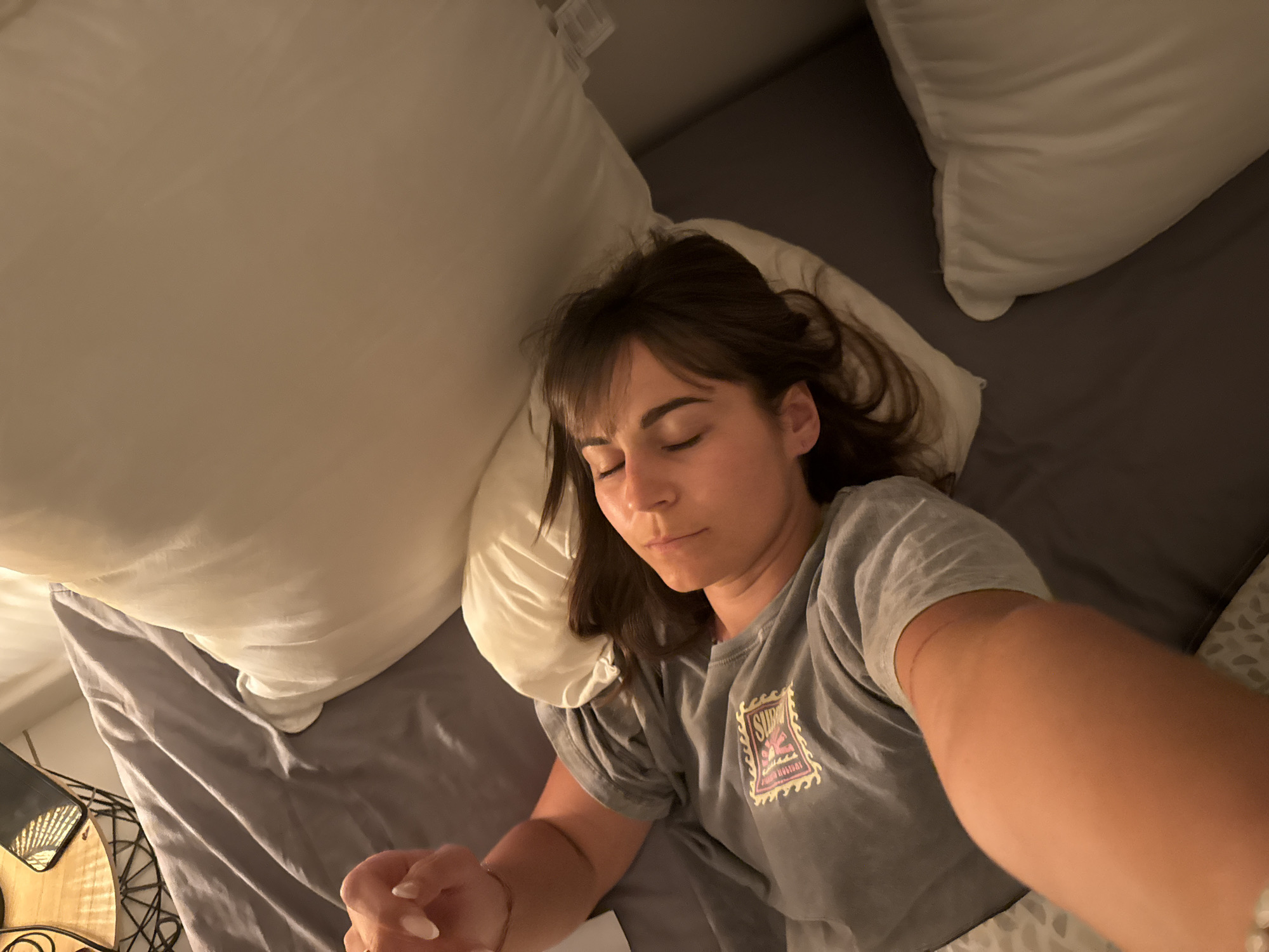 Woman rests in bed wearing Surf Bali shirt in Cannes