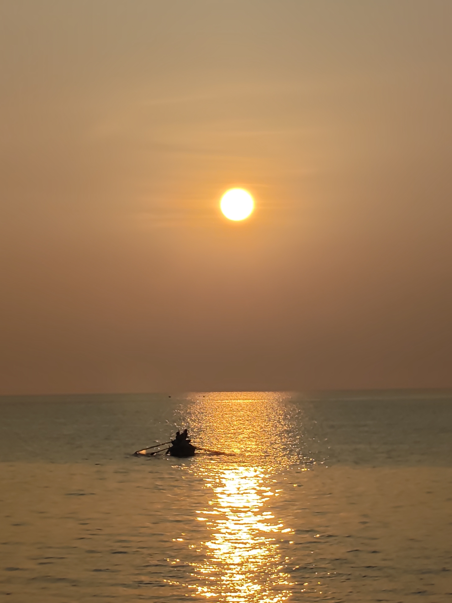 Golden sunset documented along Lhokseumawe coast with boats, beachgoer