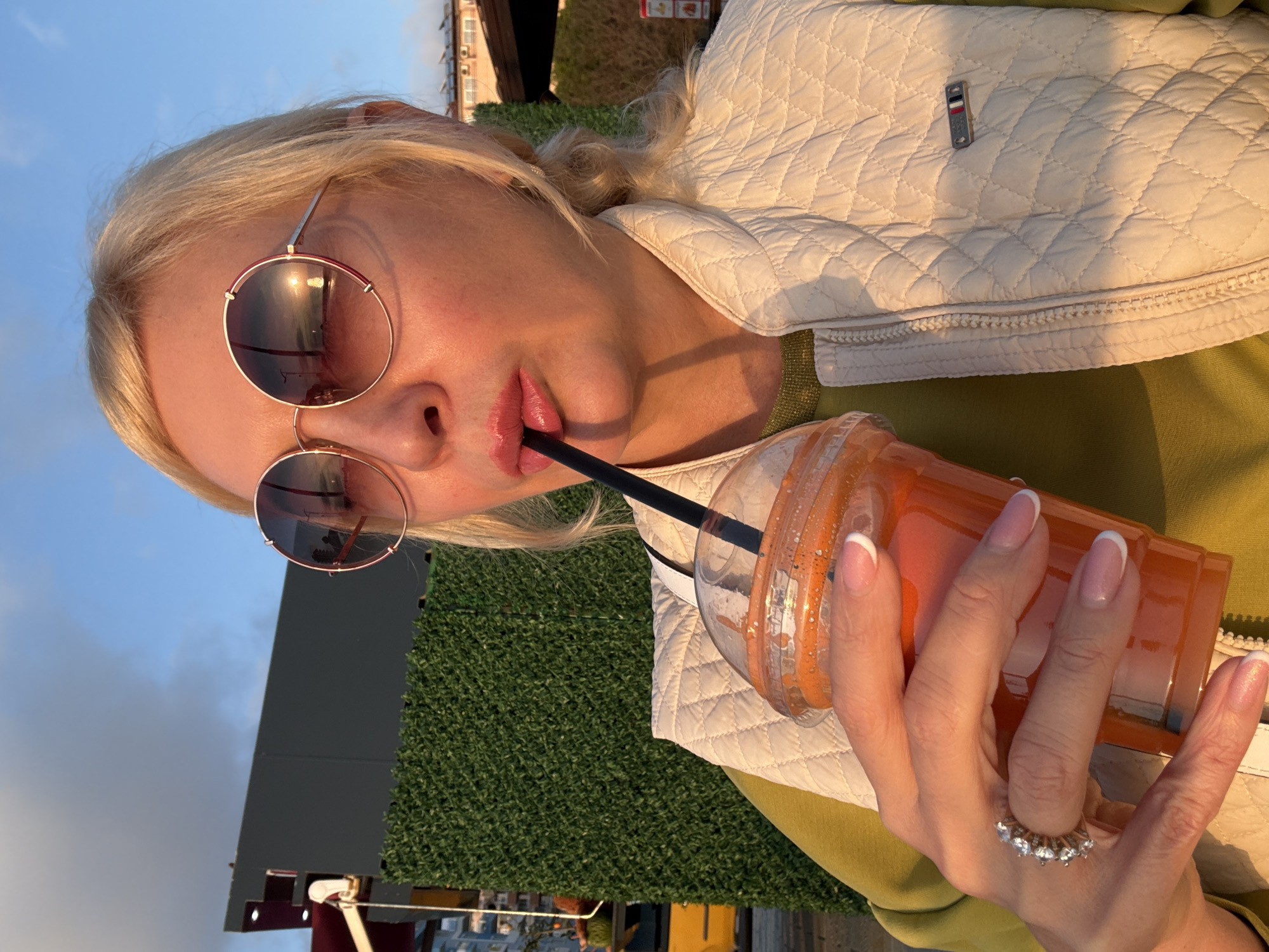 Person enjoys sunset drink at beach during golden hour
