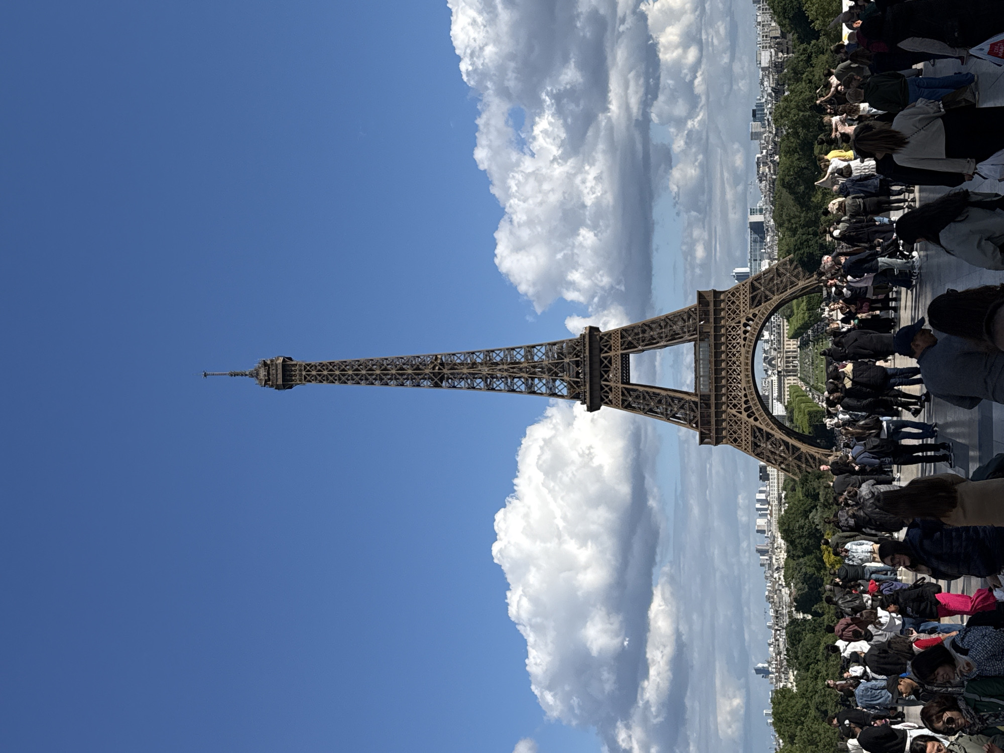 Crowds gather at Eiffel Tower on clear spring afternoon