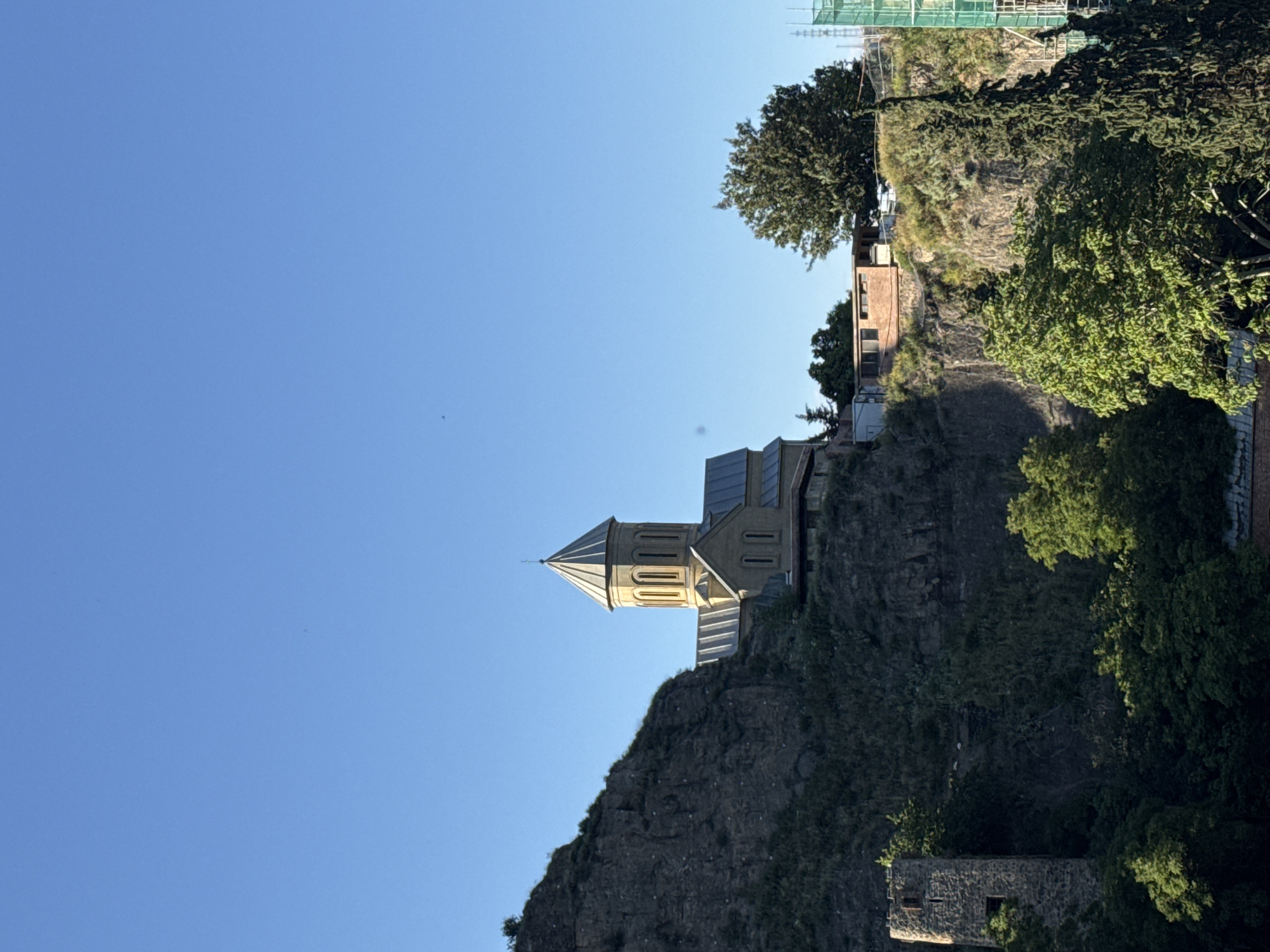 Tourist documents Tbilisi's historic cityscape during sunny afternoon