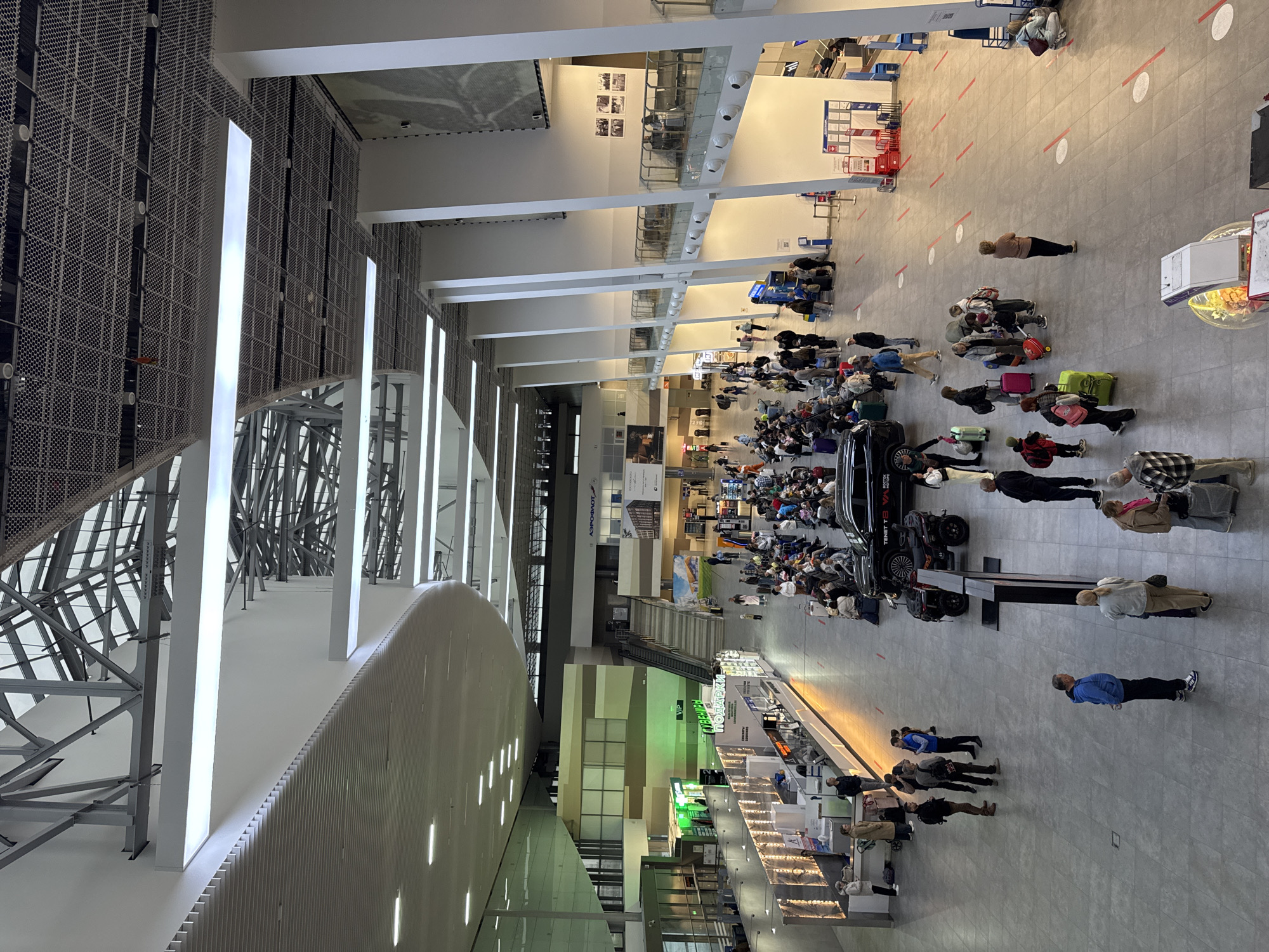 Russian airport terminal shows normal passenger activity, multilingual signage