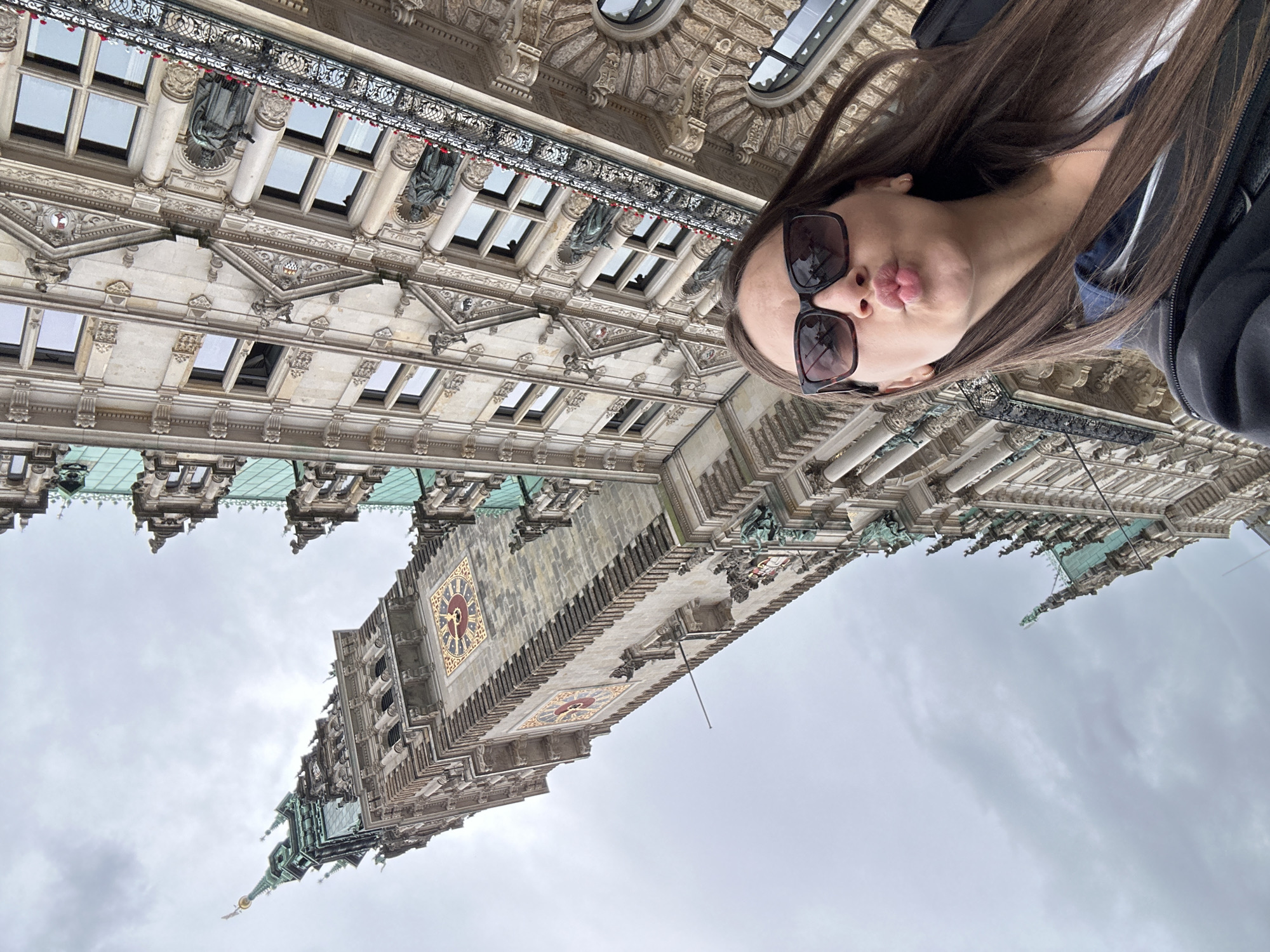 Tourists document Hamburg City Hall amid street performances