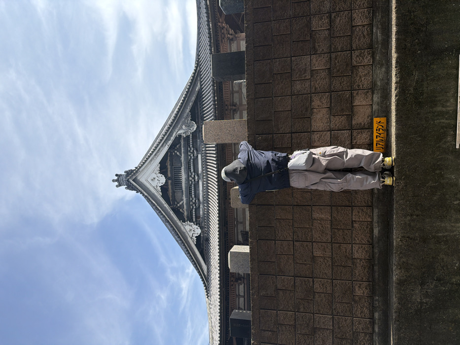 Person rests against wall near traditional building in Taito
