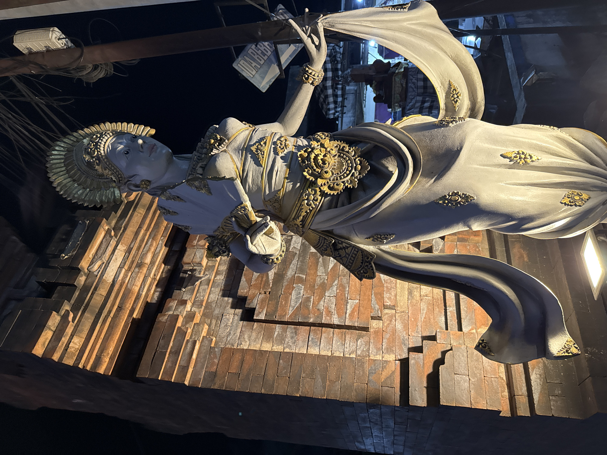 A Denpasar night: streets, statues, flowers, and winding down
