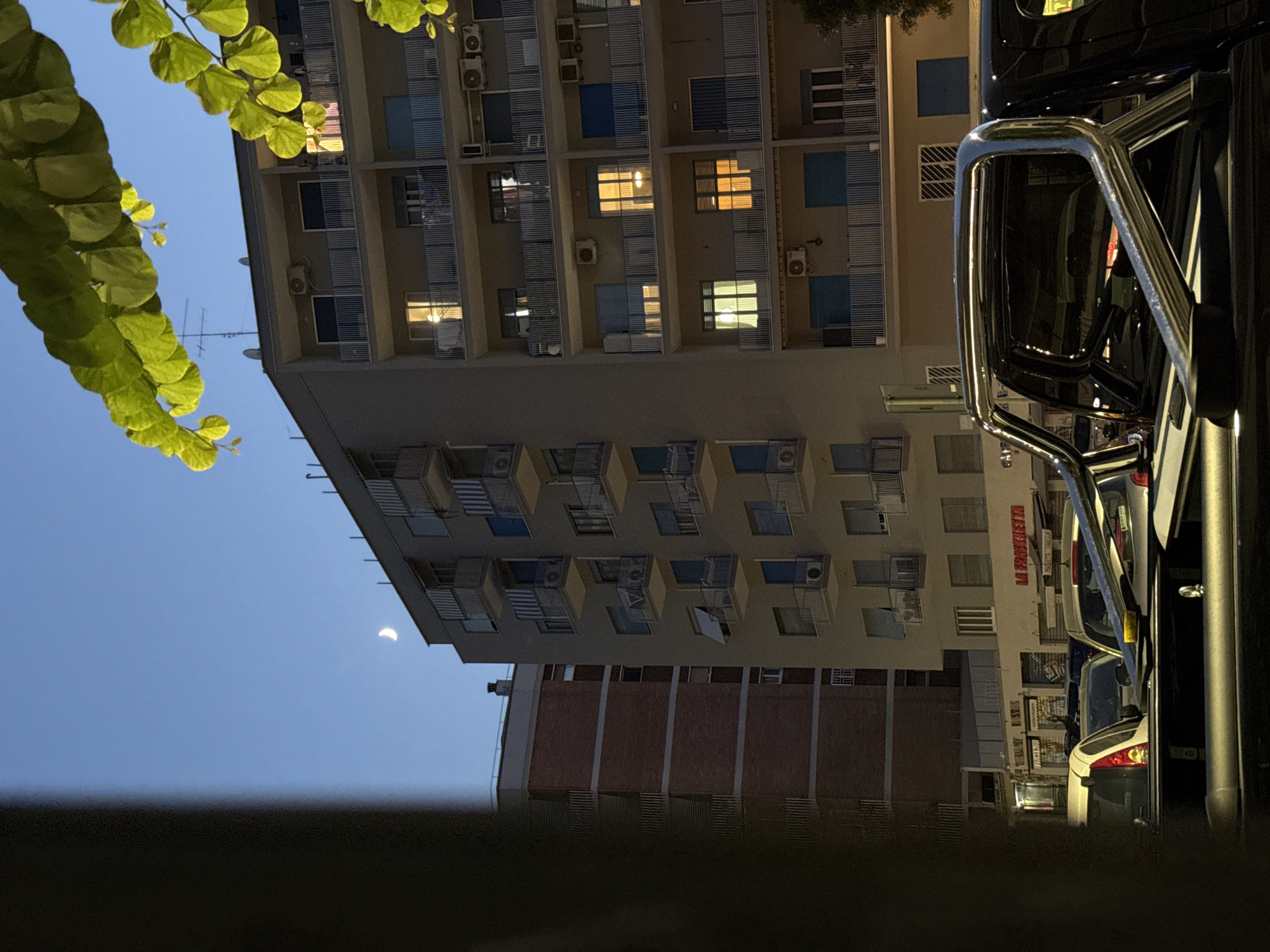 Rome street at dusk, crescent moon over parked pickup truck