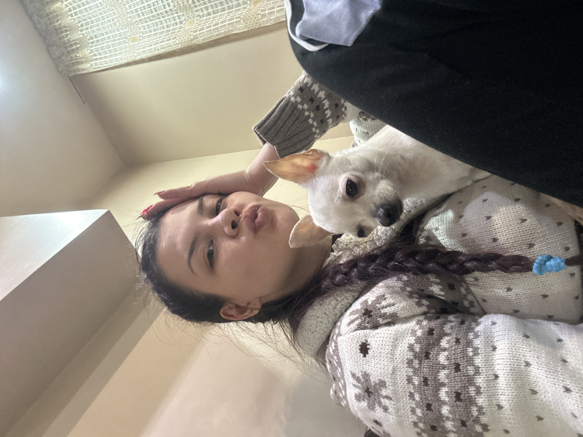 Person poses with small white dog in affectionate moment