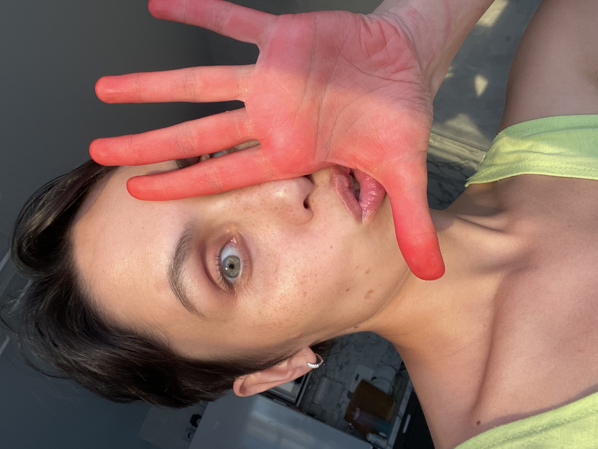 Person photographed with red-tinted hand covering face in Izhevsk