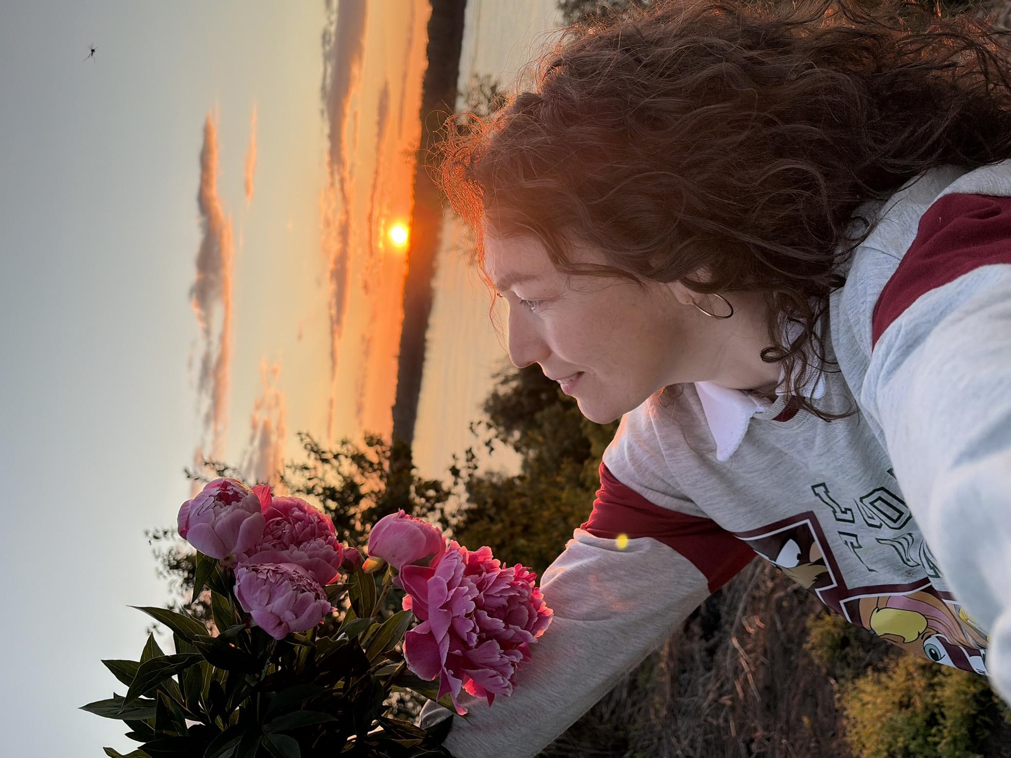 Woman poses with pink peonies during sunset in Ольховка
