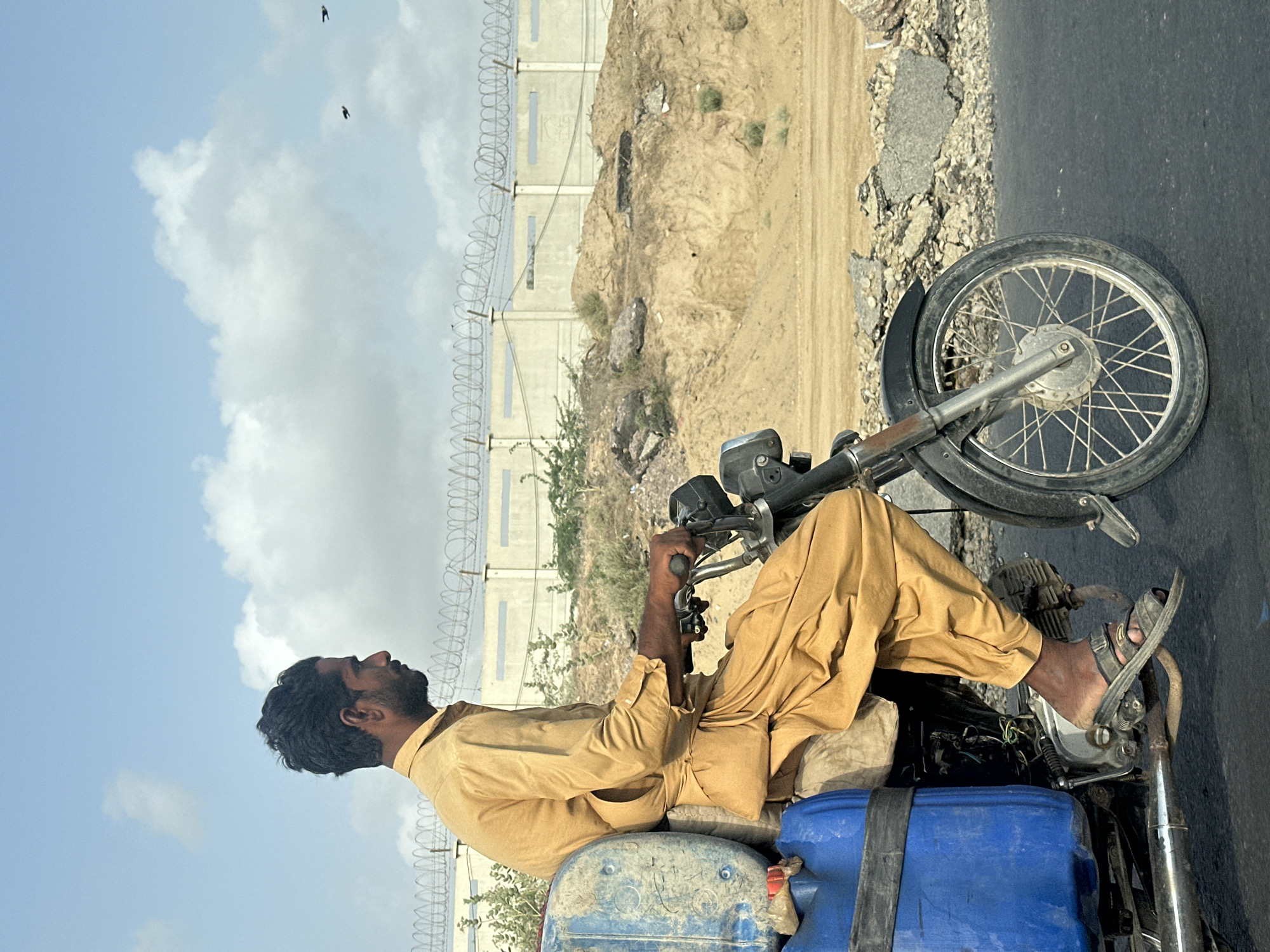 Motorcycle hauling large plastic barrels through Winder, Pakistan
