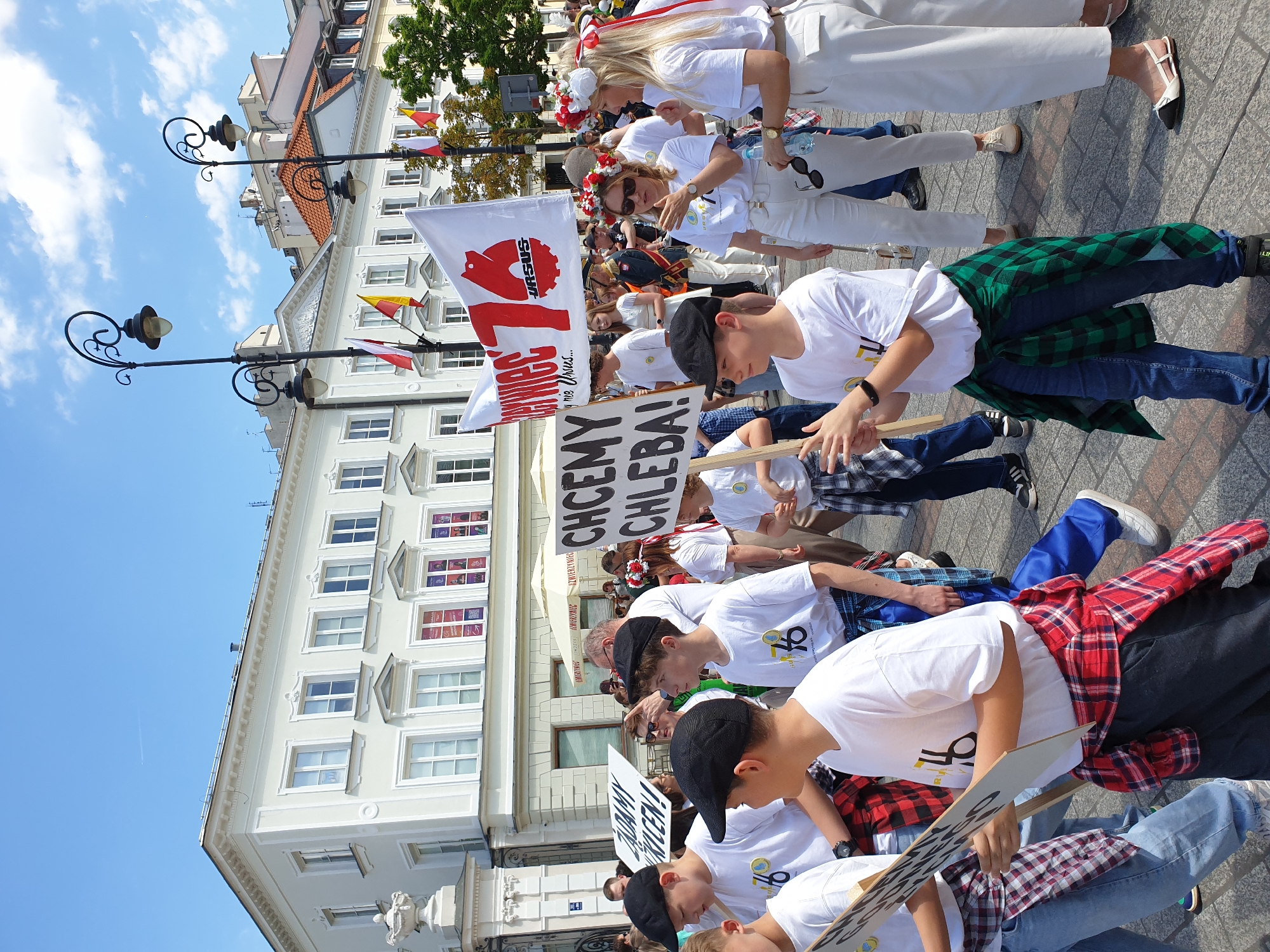 Folk dancers and marching band parade through historic Warsaw street