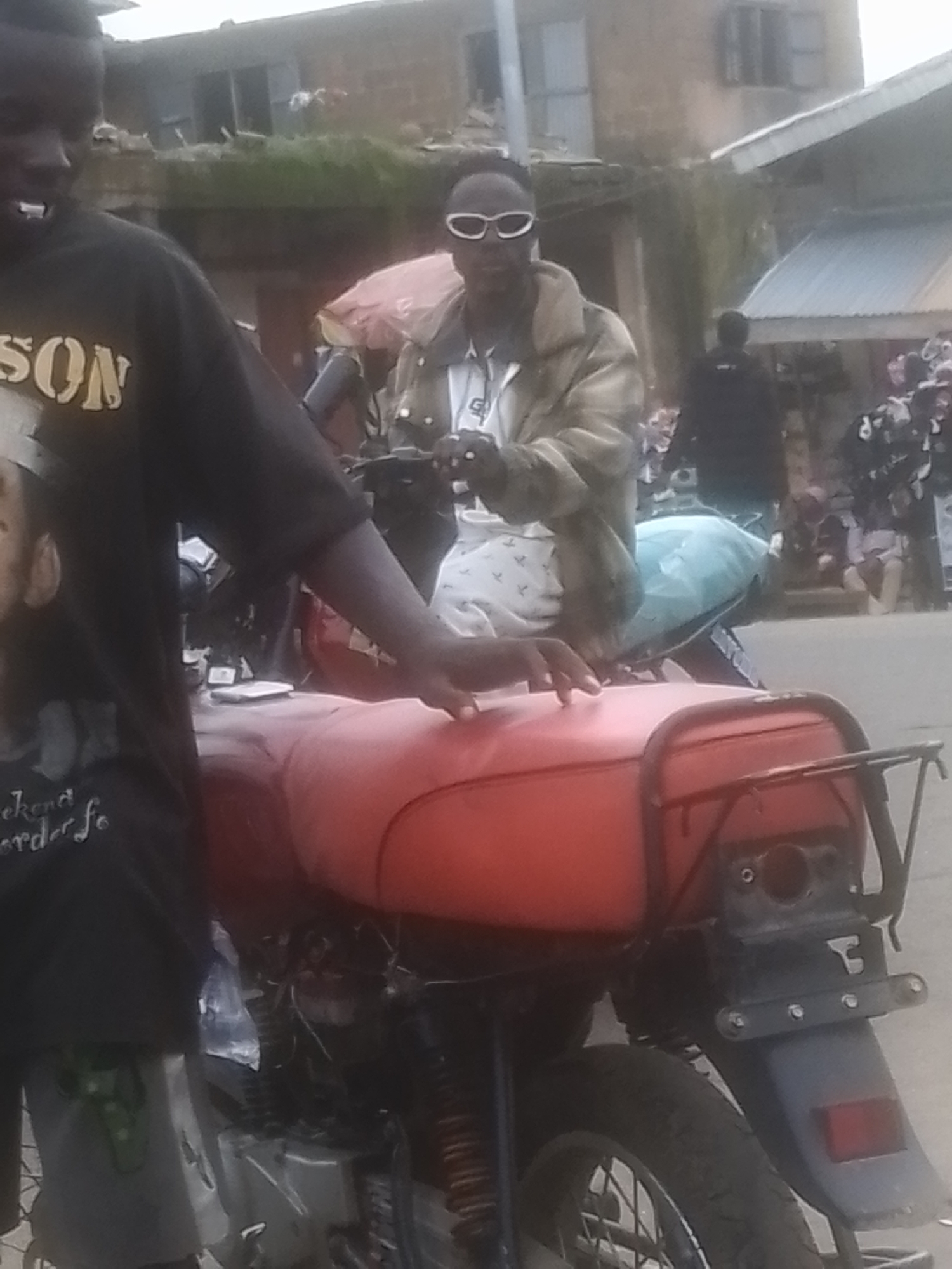 Busy street market with motorcycles, vendors, and passing foot traffic