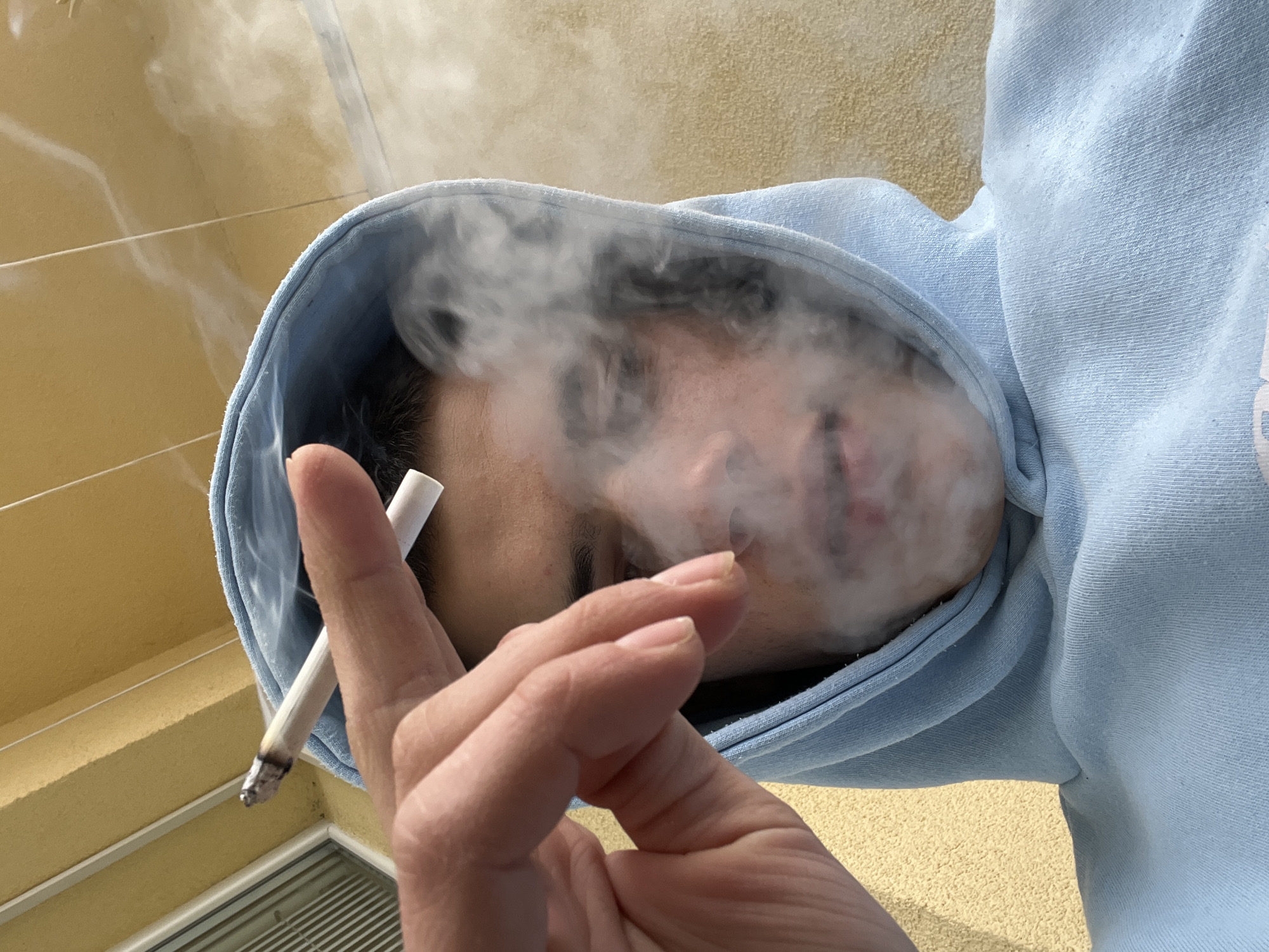 Young person smokes, drinks coffee on Sopot balcony amid overcast skies