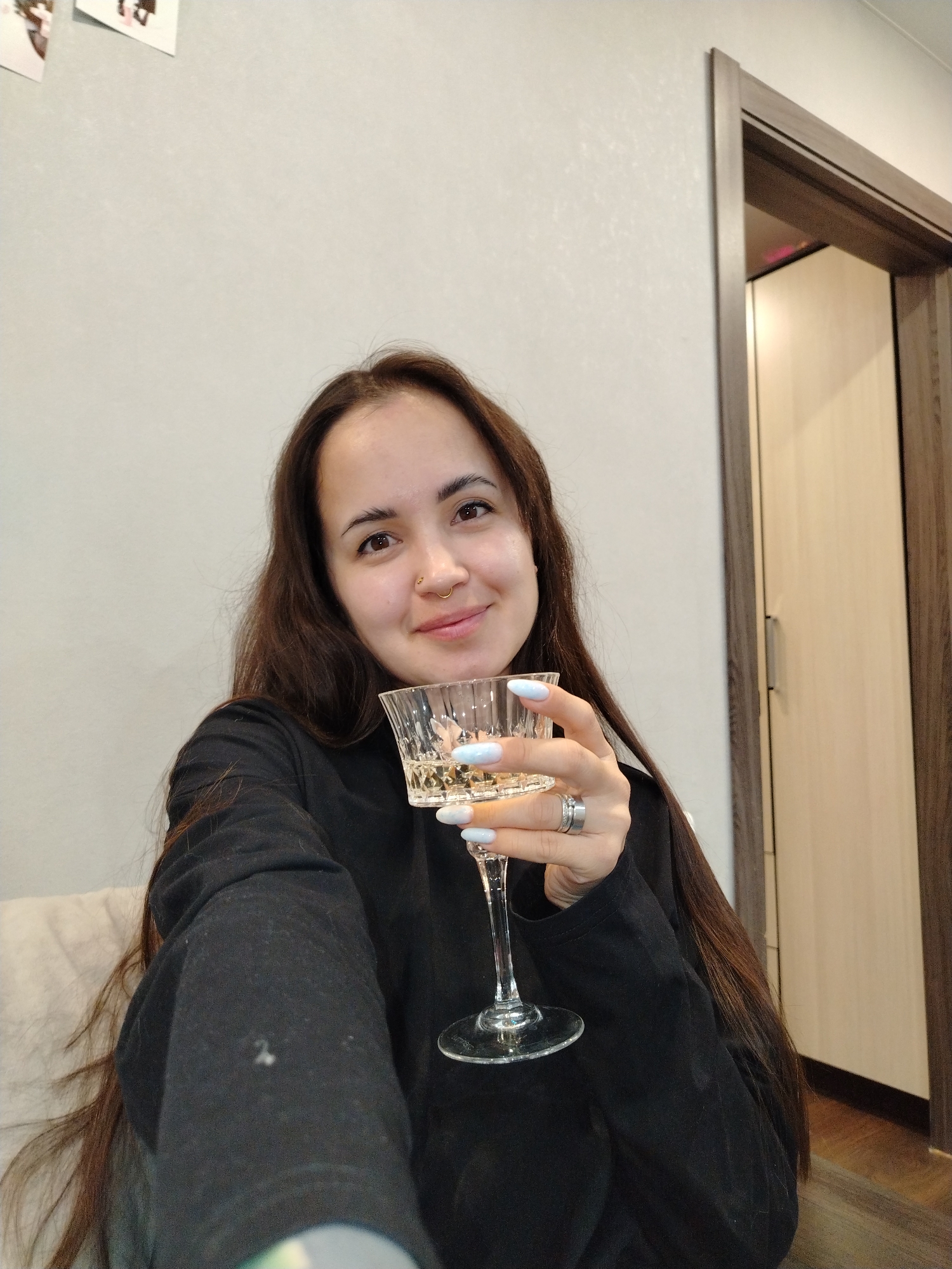 Woman enjoys wine, poses playfully indoors in Noviy, Russia