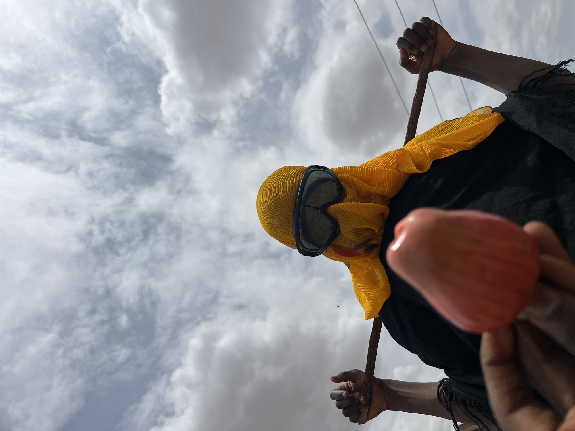 Person in yellow headwear photographed with stick in Udu