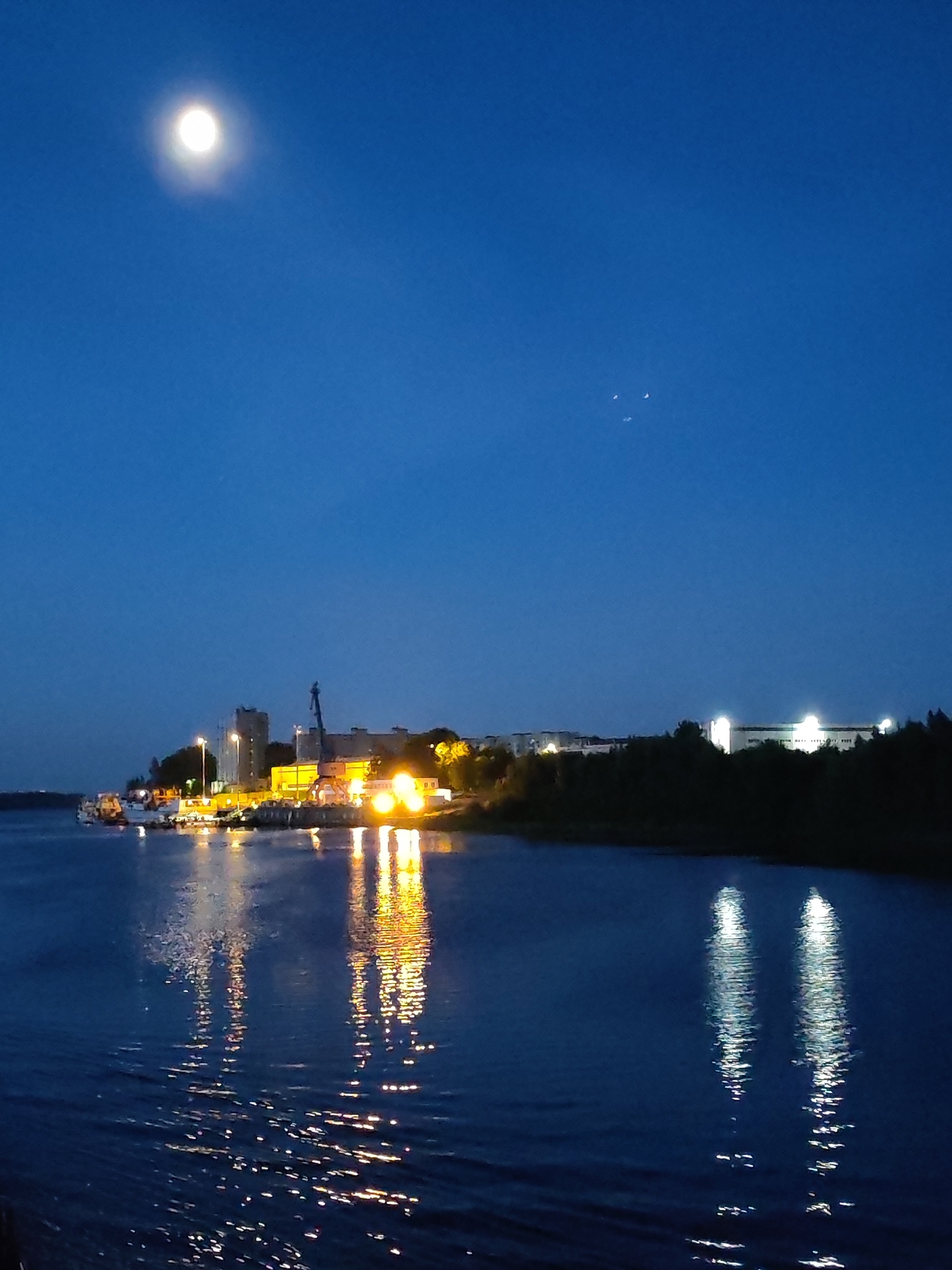 Full moon and passenger ship on a glowing waterfront at twilight