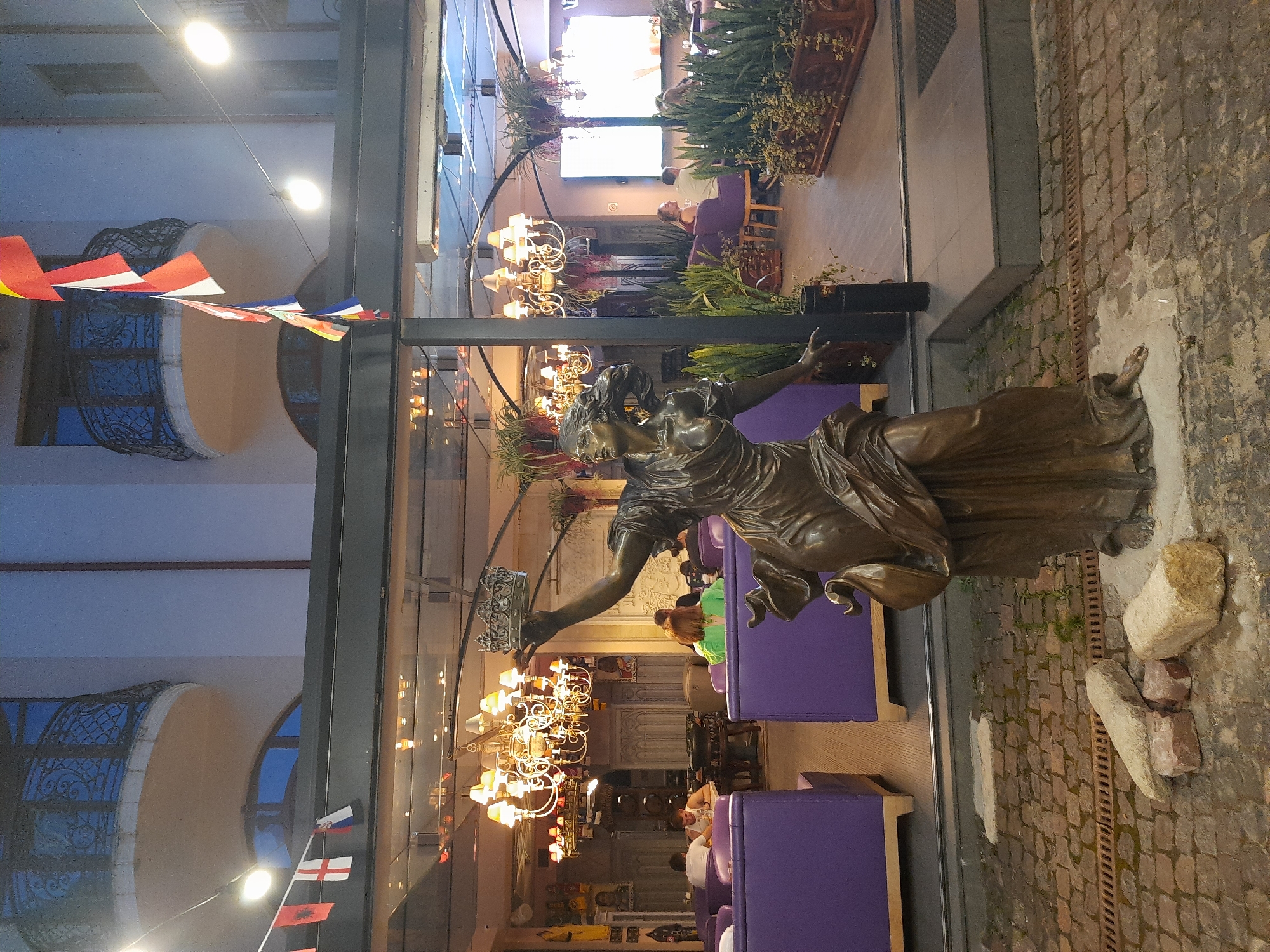 Bronze statue on cobblestone street outside a Lviv cafe