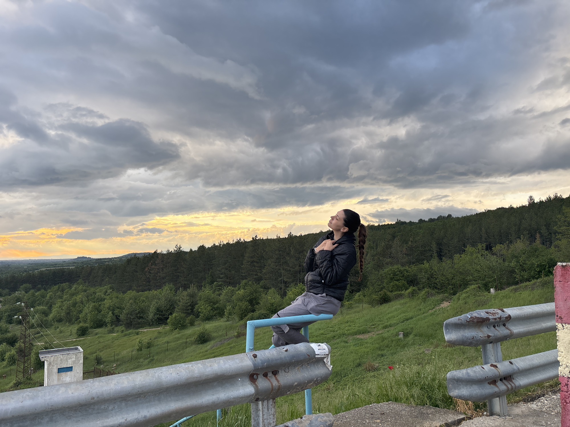 Woman spends quiet moments at Bulgarian reservoir overlook with poppy