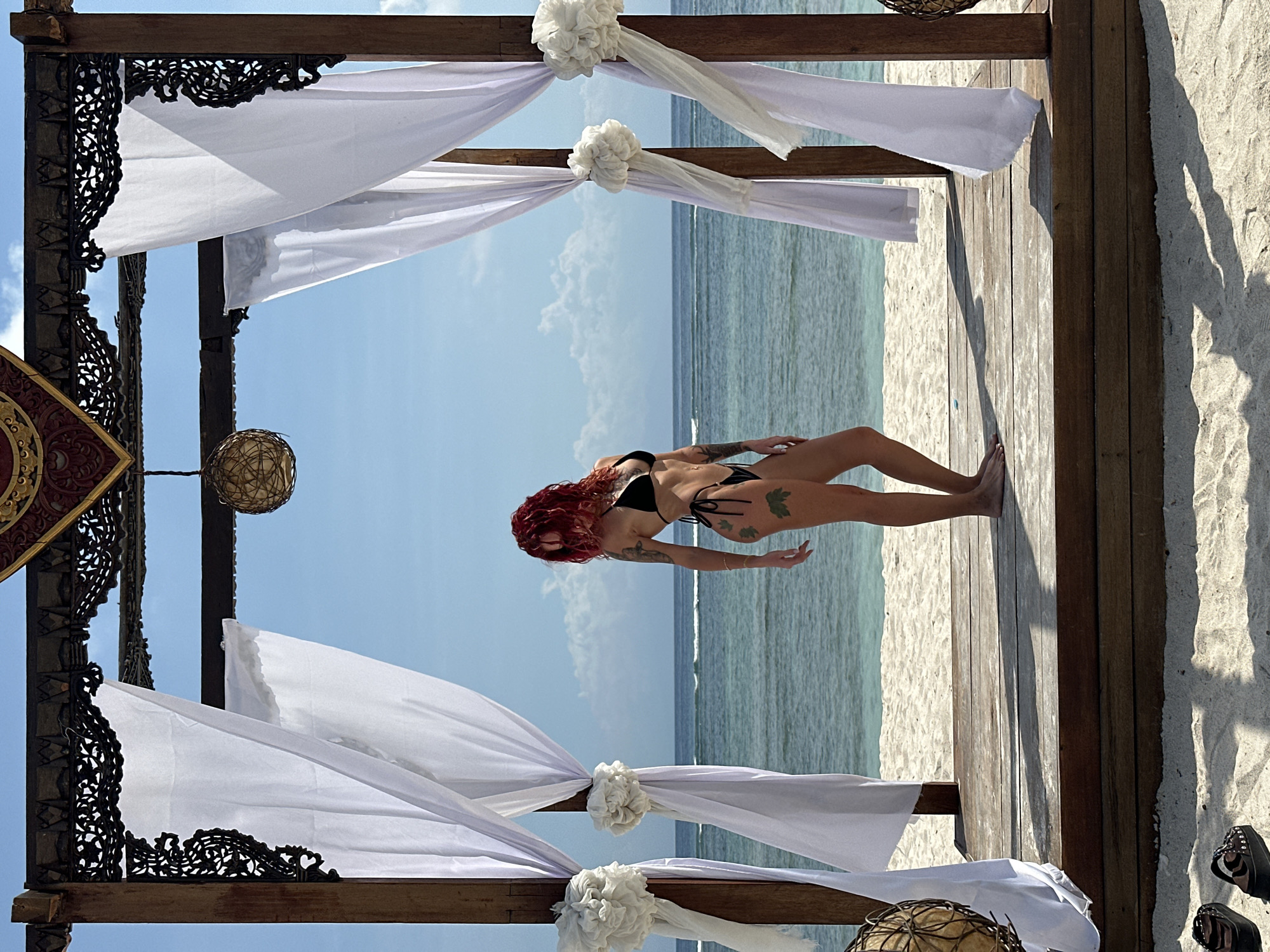 Woman poses on wooden deck overlooking ocean in Indonesia
