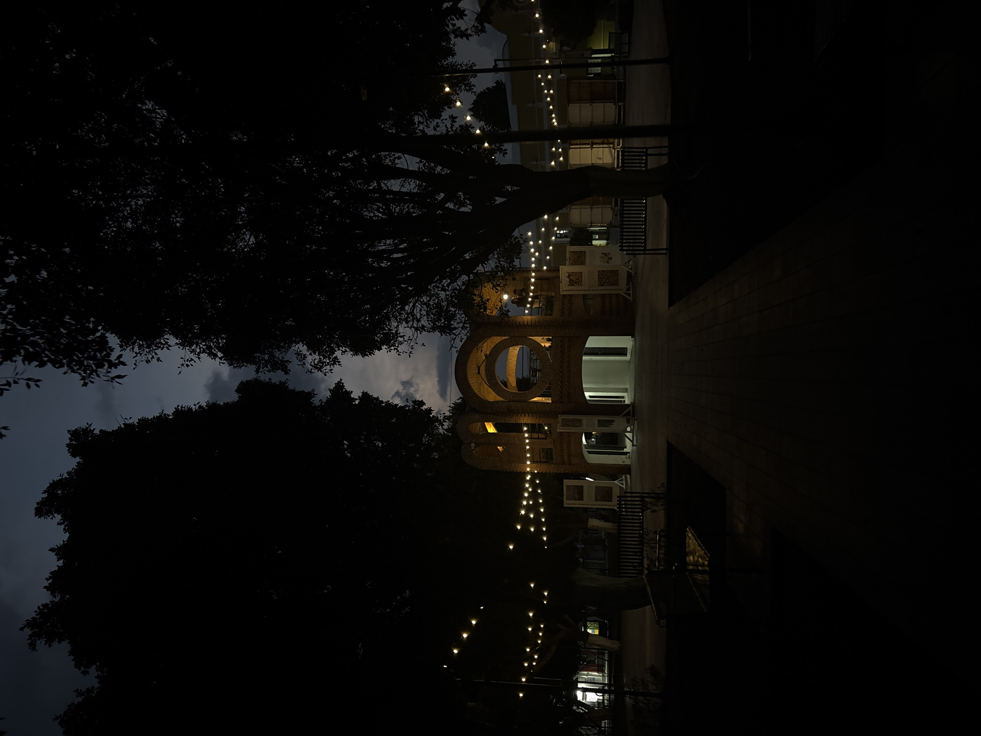Illuminated brick archway with string lights observed at night