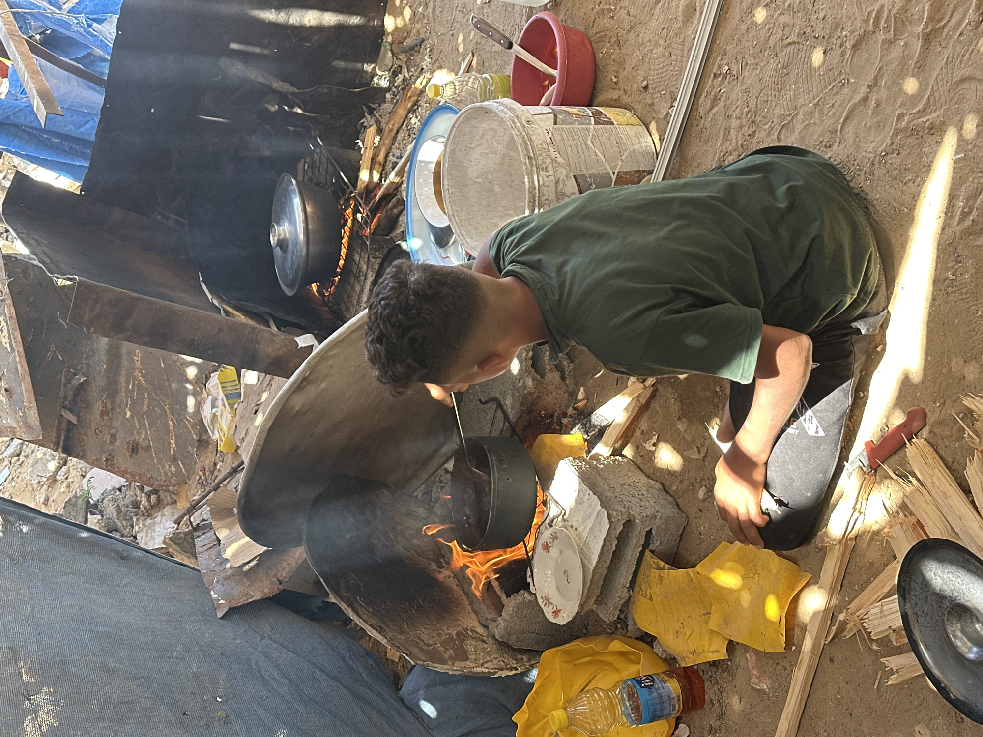 Person cooks over makeshift fire in damaged Gaza area