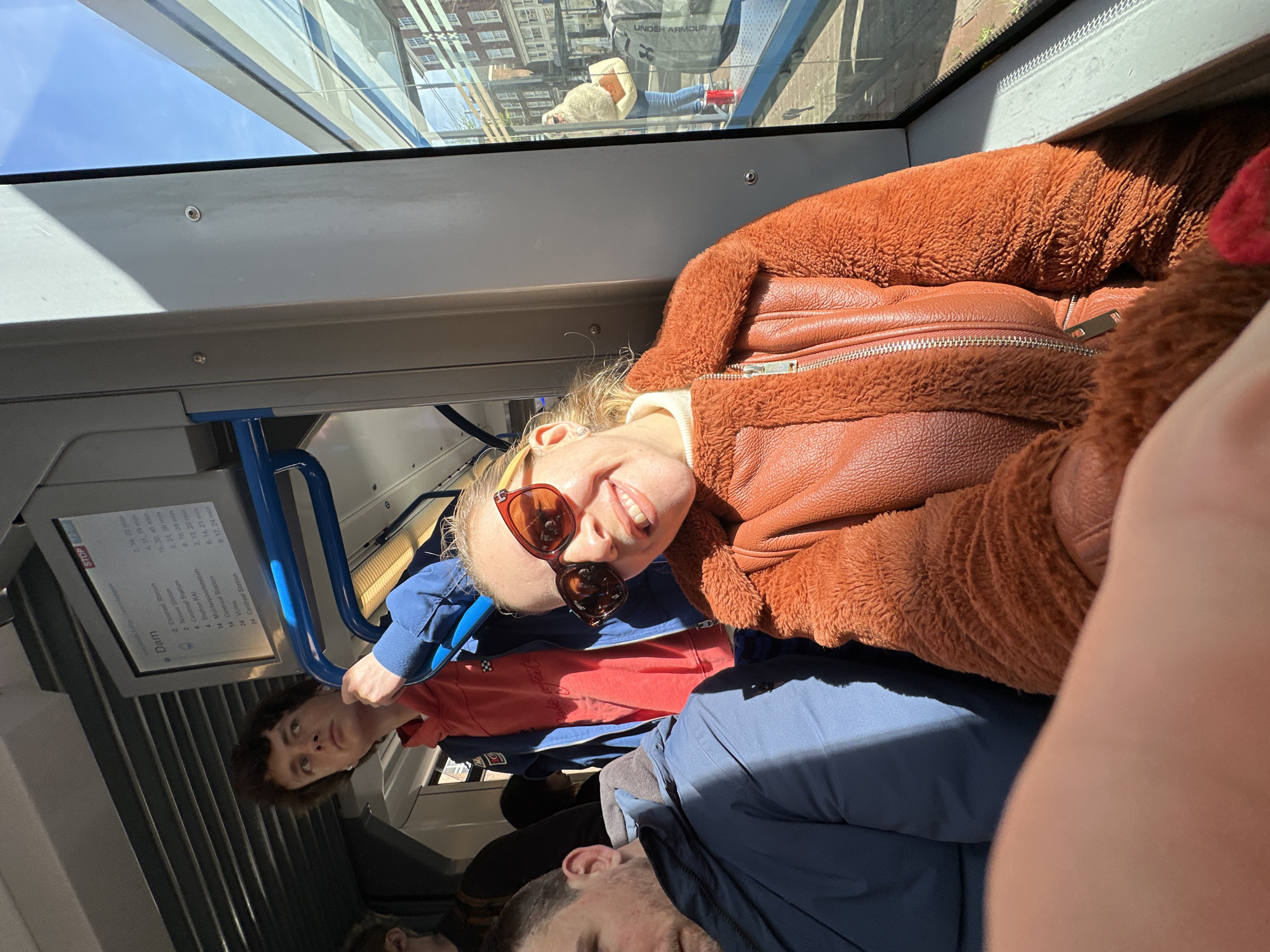 Woman smiles on Amsterdam tram during sunny morning commute