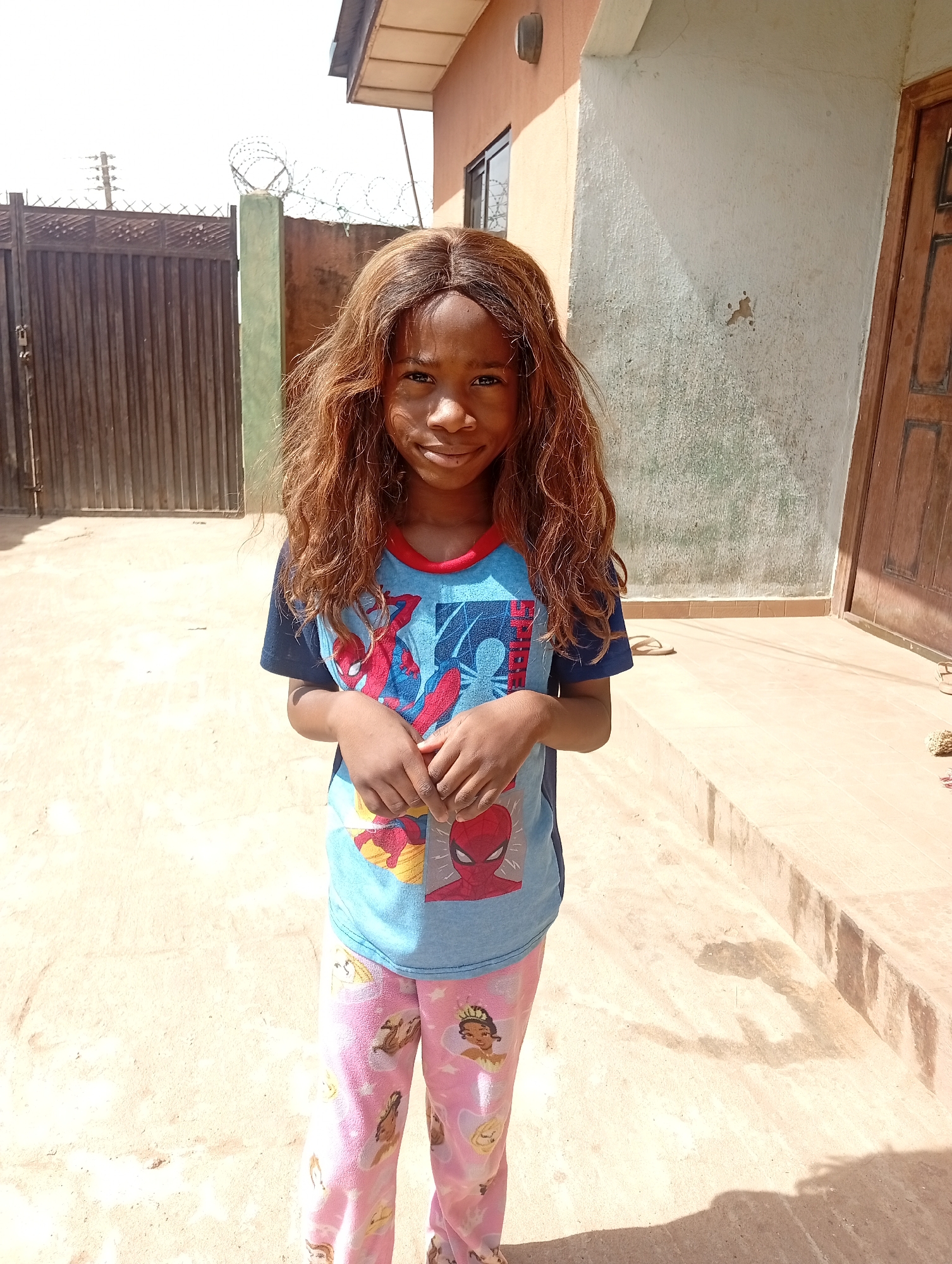 Girl in Spiderman shirt plays in Sabon Tasha courtyard