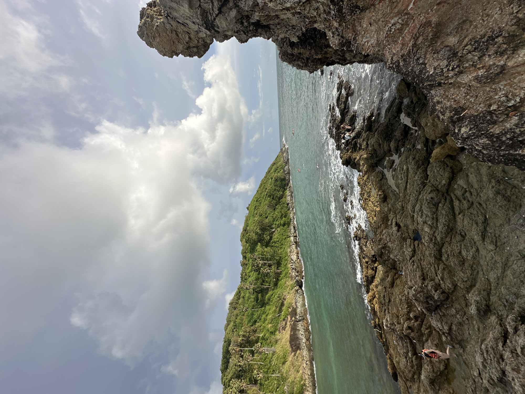 Rawai's rugged coastline: waves, cliffs, and a paraglider overhead