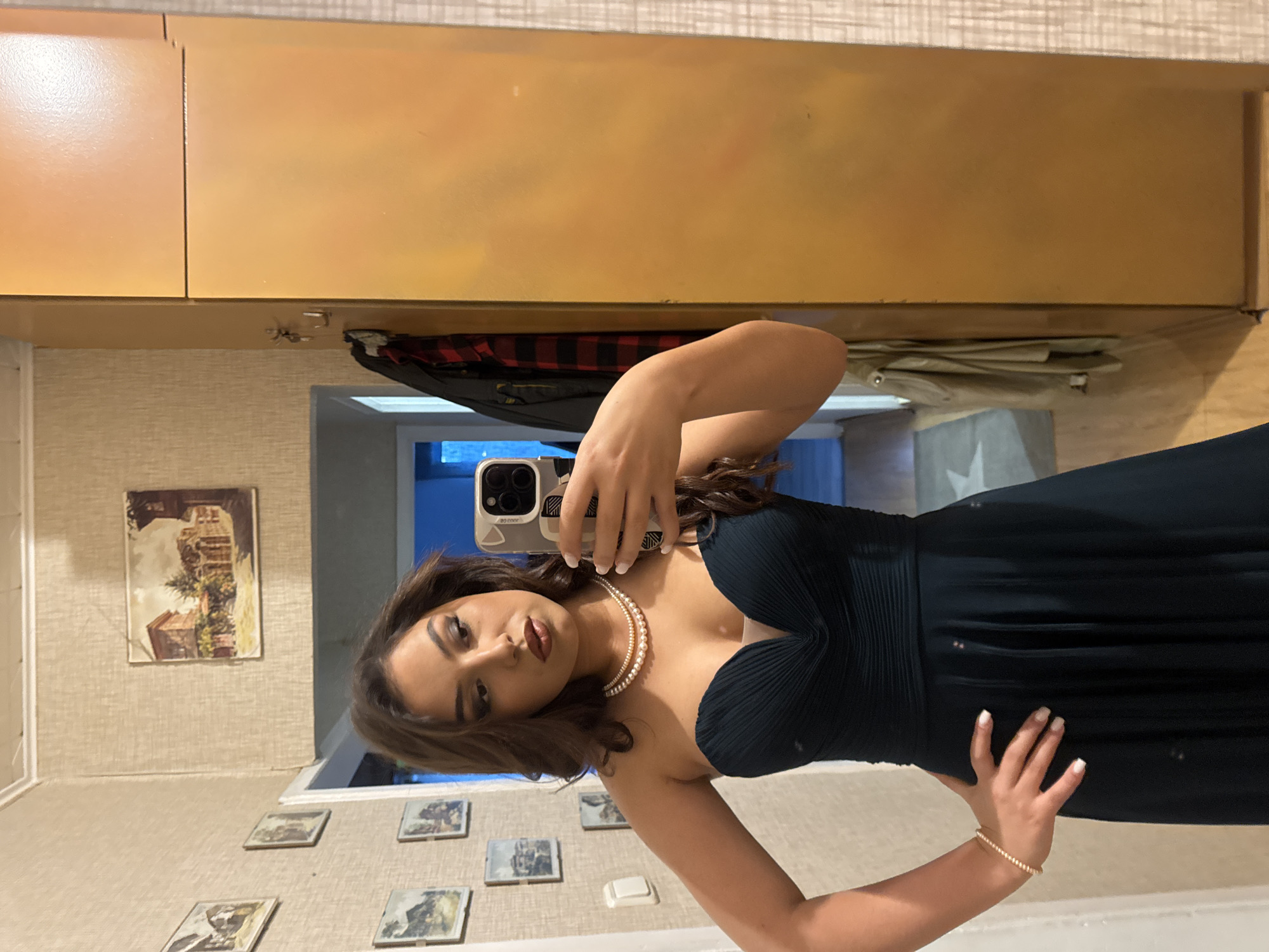 Woman photographs herself in formal green dress and pearls