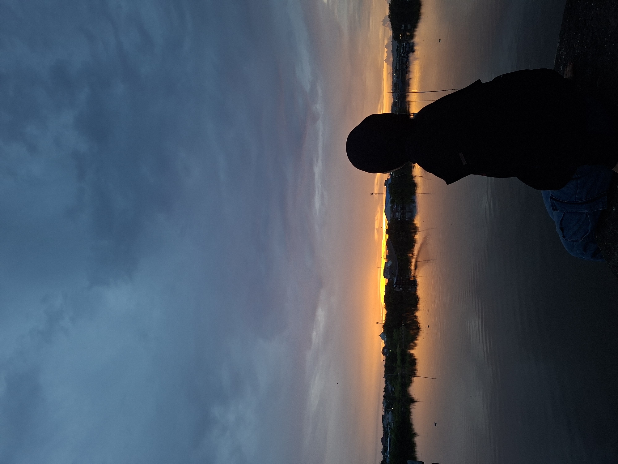 Person enjoys sunset moment with kitten at Lhokseumawe waterfront