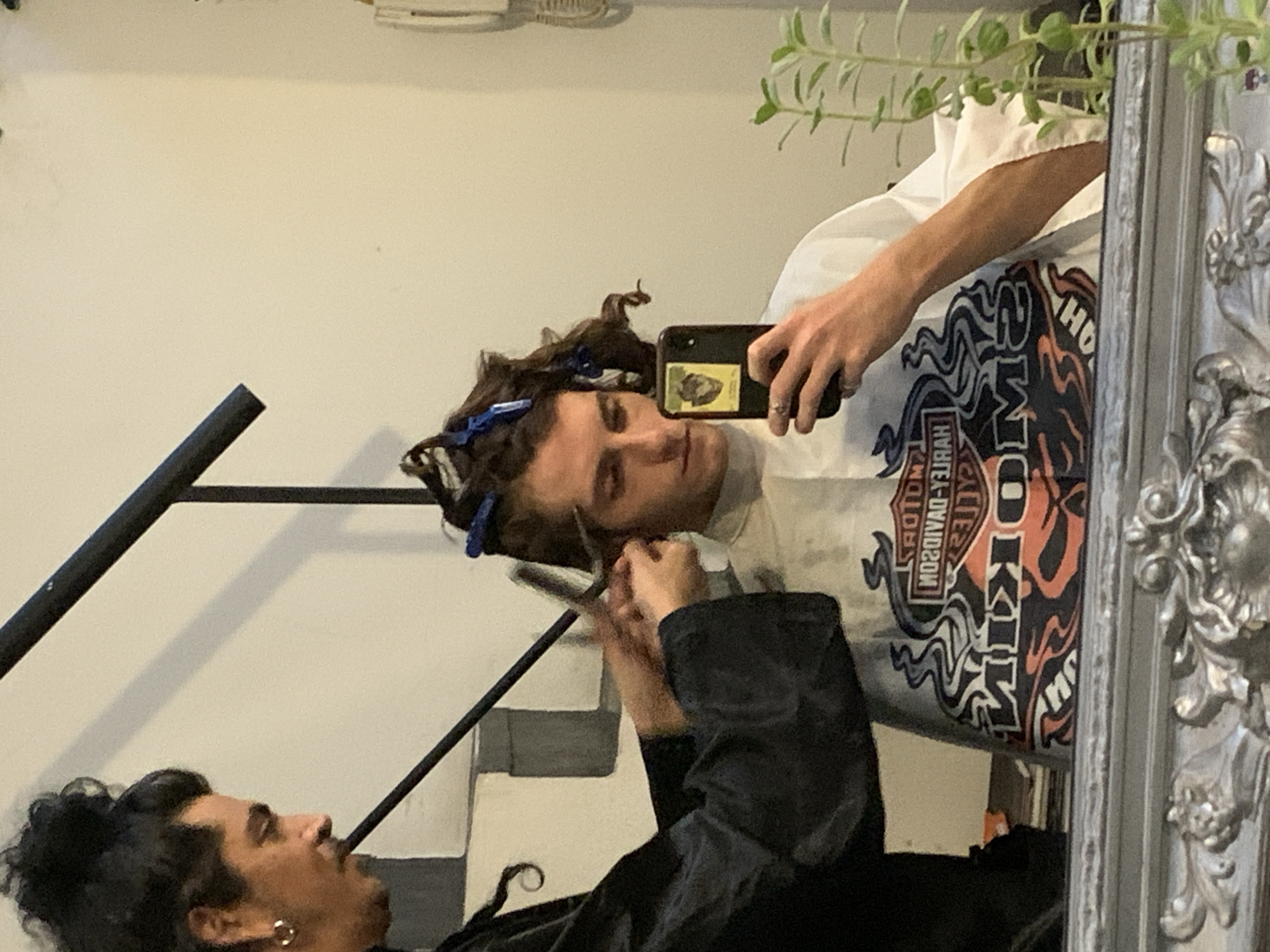 Mirror reflection captures two people, one holding scissors in Buenos Aires