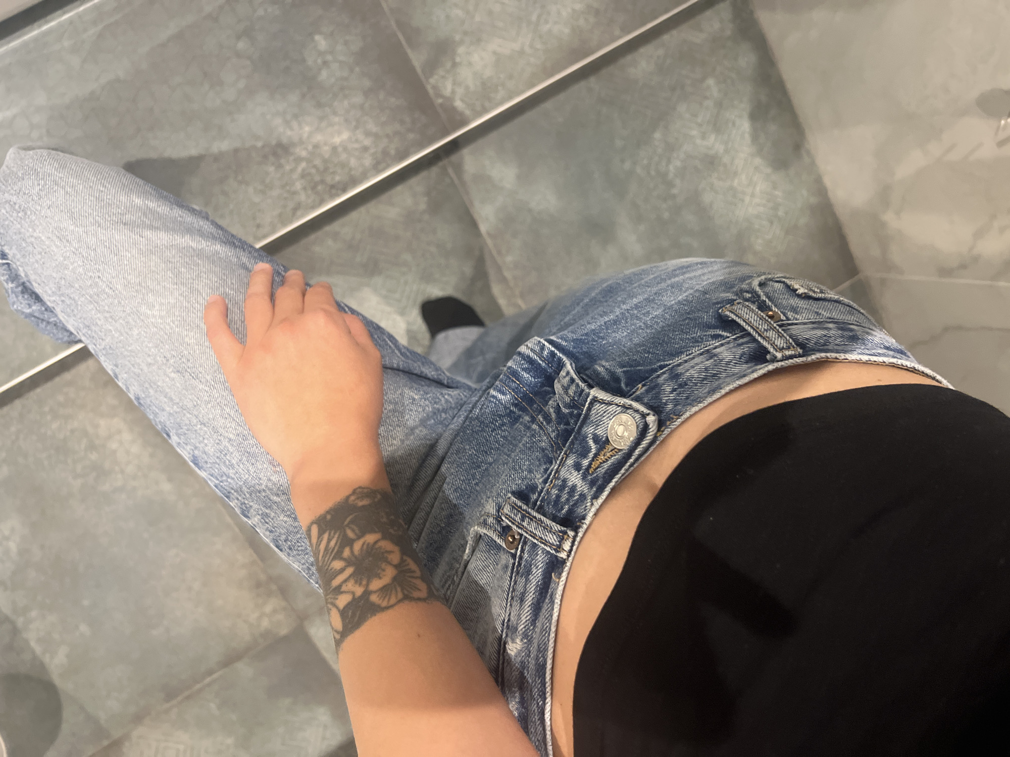 Person with floral wrist tattoo observed on gray tiles