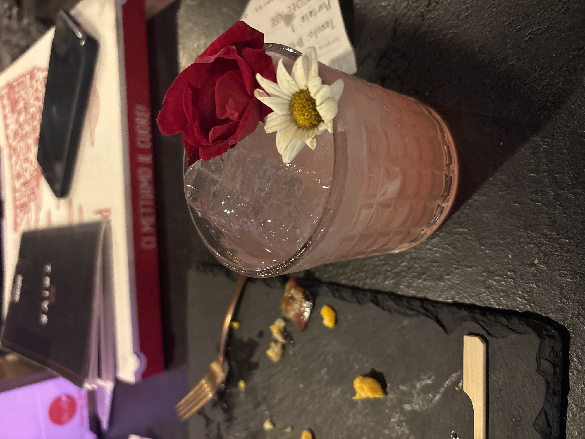 Floral-garnished cocktail documented in Milan evening dining scene