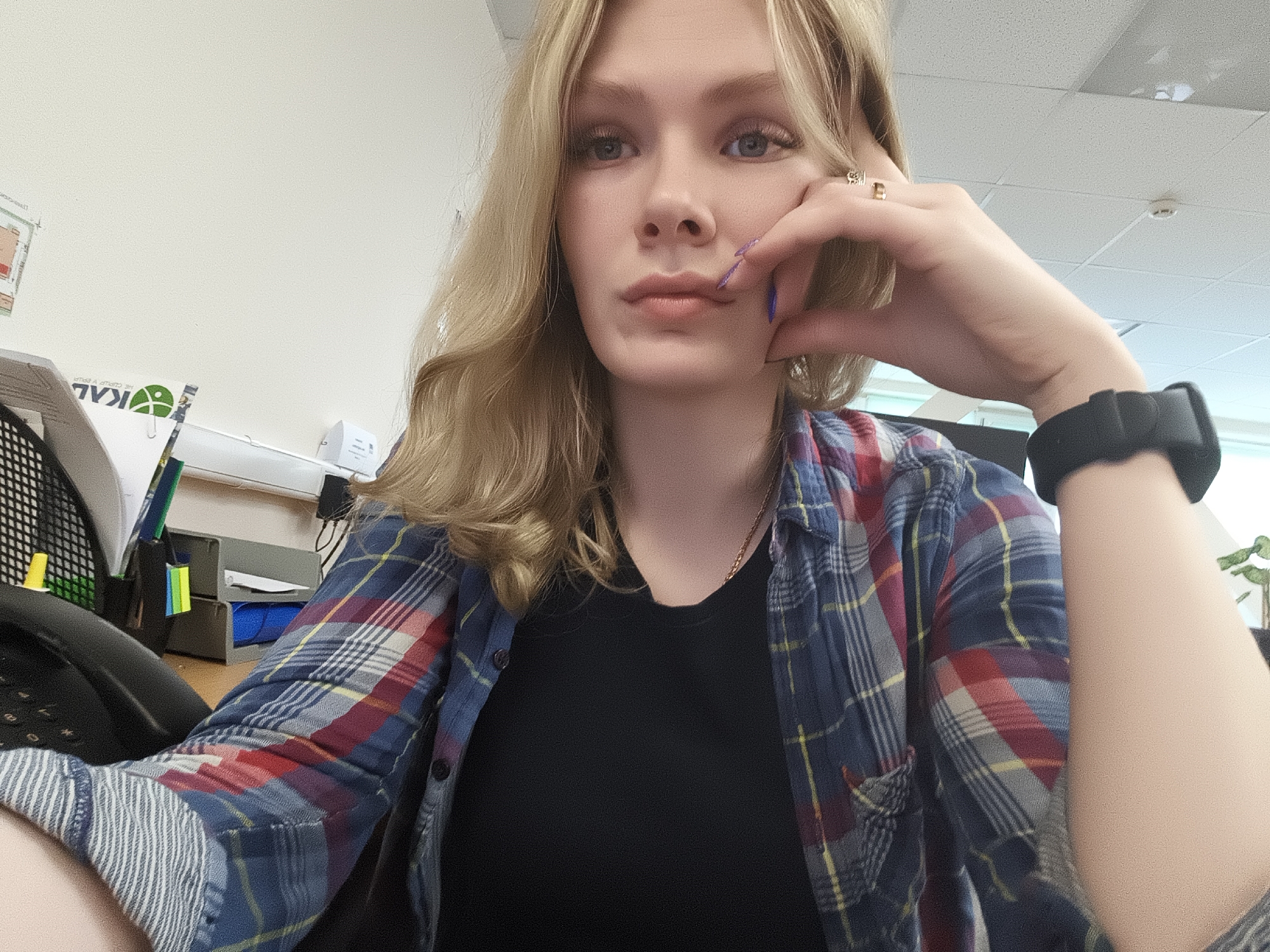 Woman takes selfie in office wearing plaid flannel