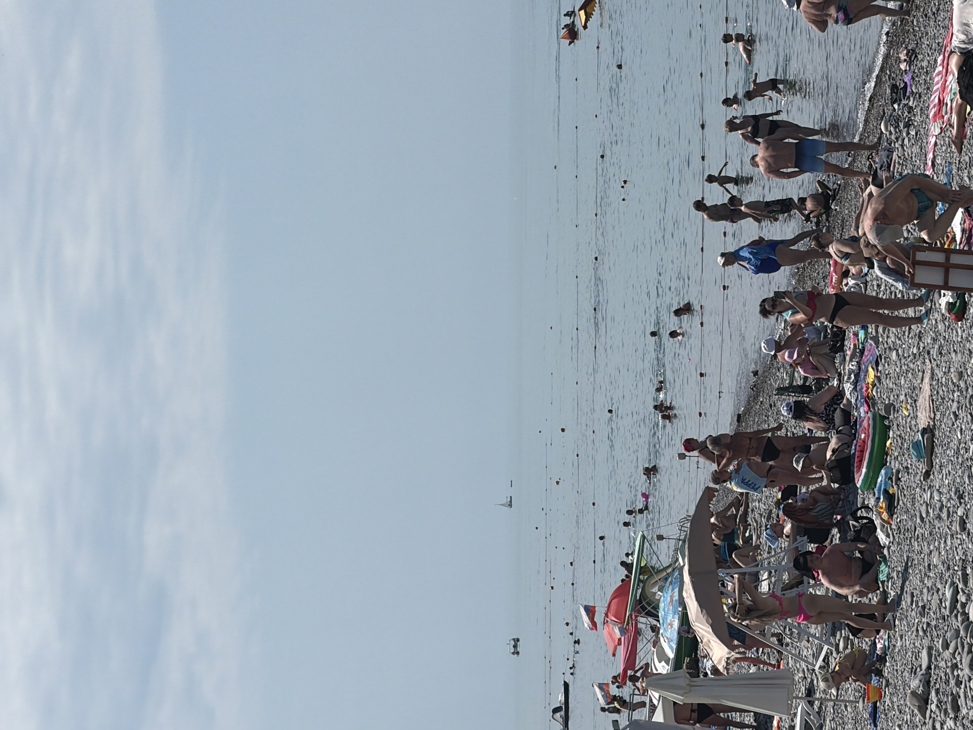 Busy morning at Sochi beach features parasailing, sunbathers