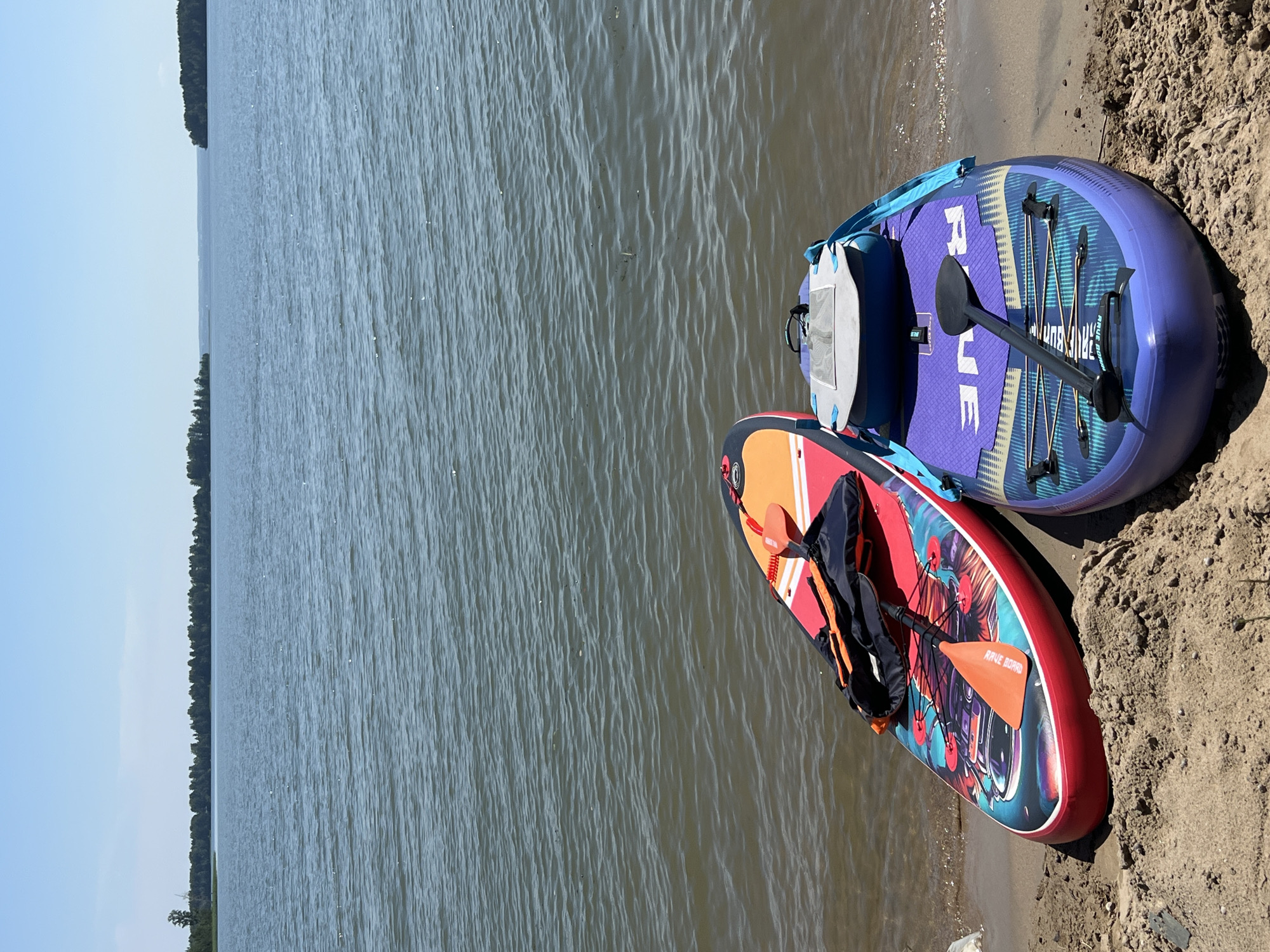 Paddleboards and gear lined up on a calm Russian lakeside