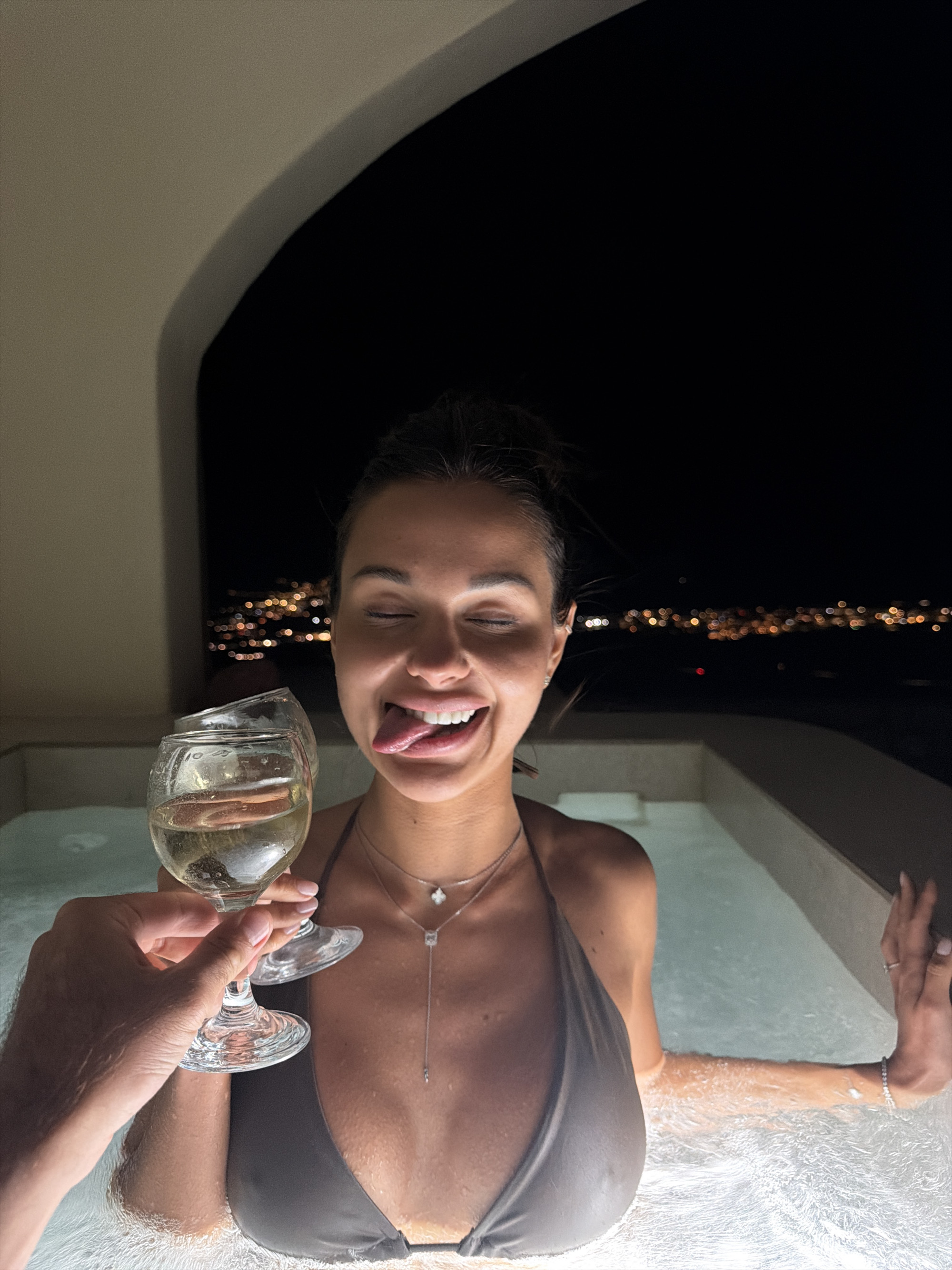 Nighttime hot tub drinks with Santorini lights in the background