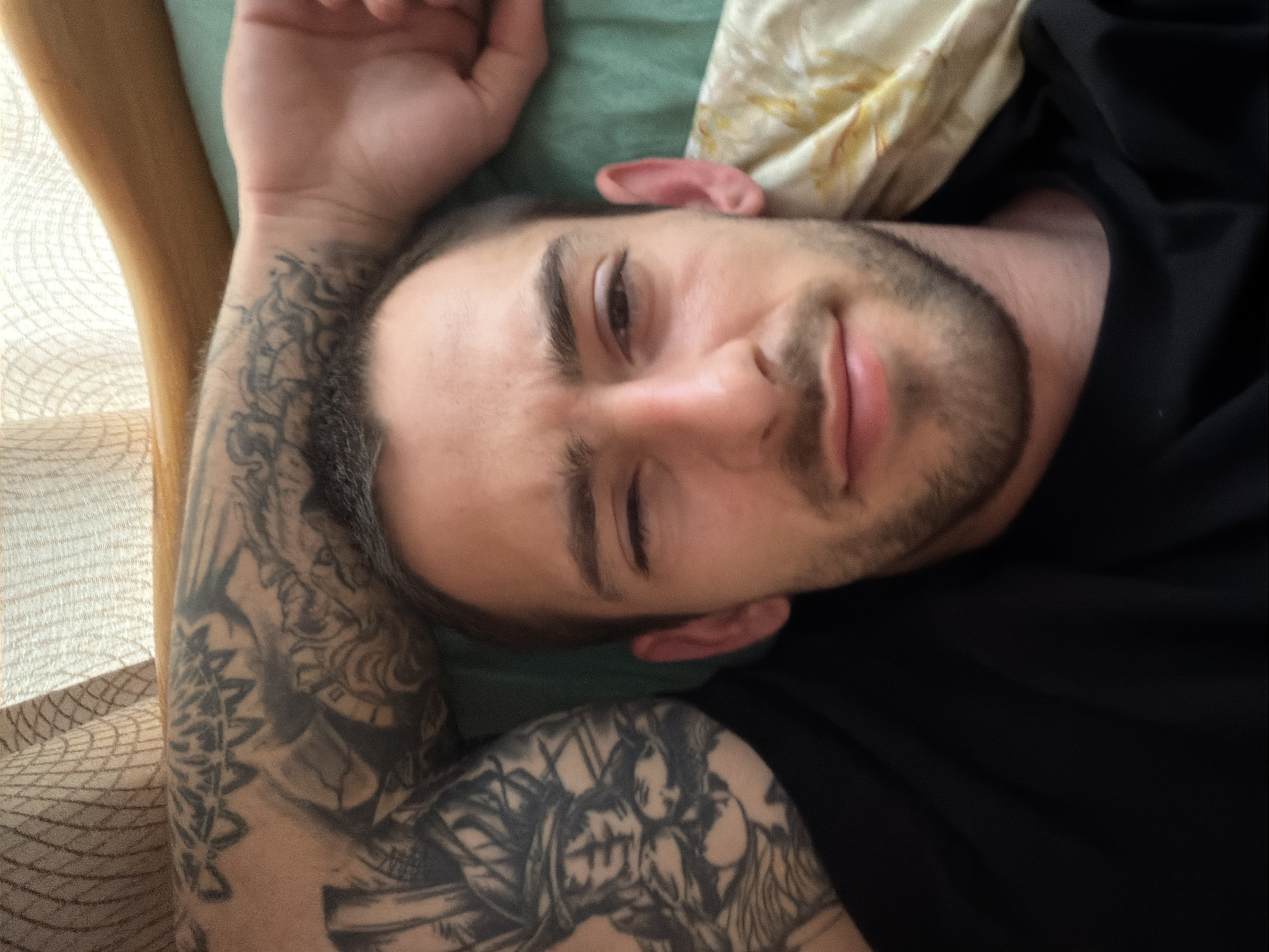 Tattooed man resting on bed in Plovdiv