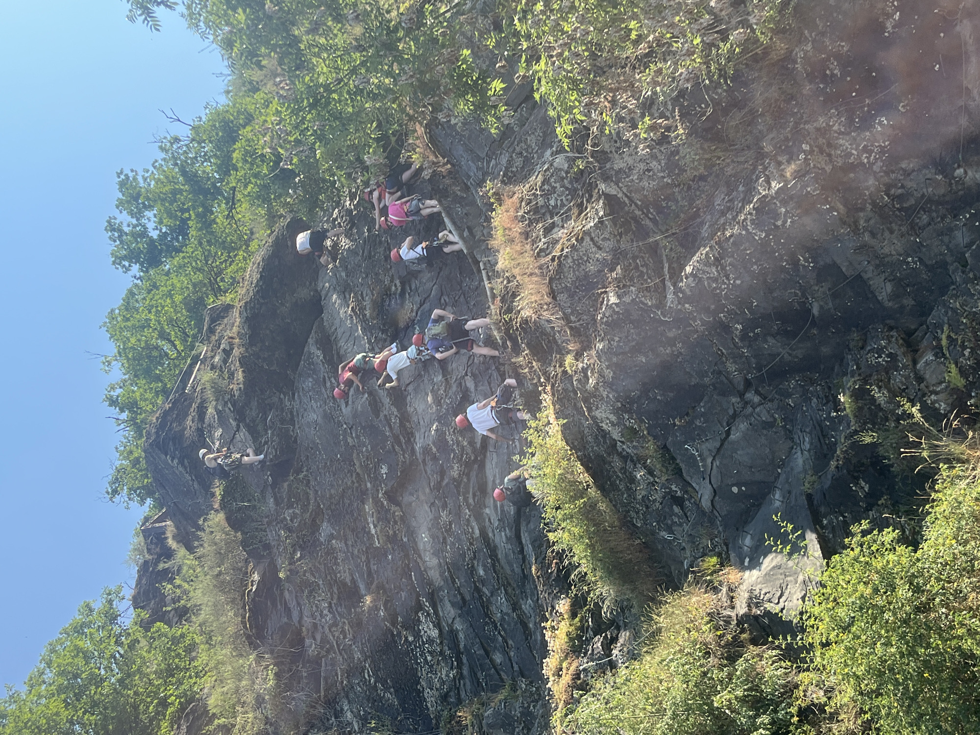 Via ferrata group climbs a steep cliff face in mountain terrain
