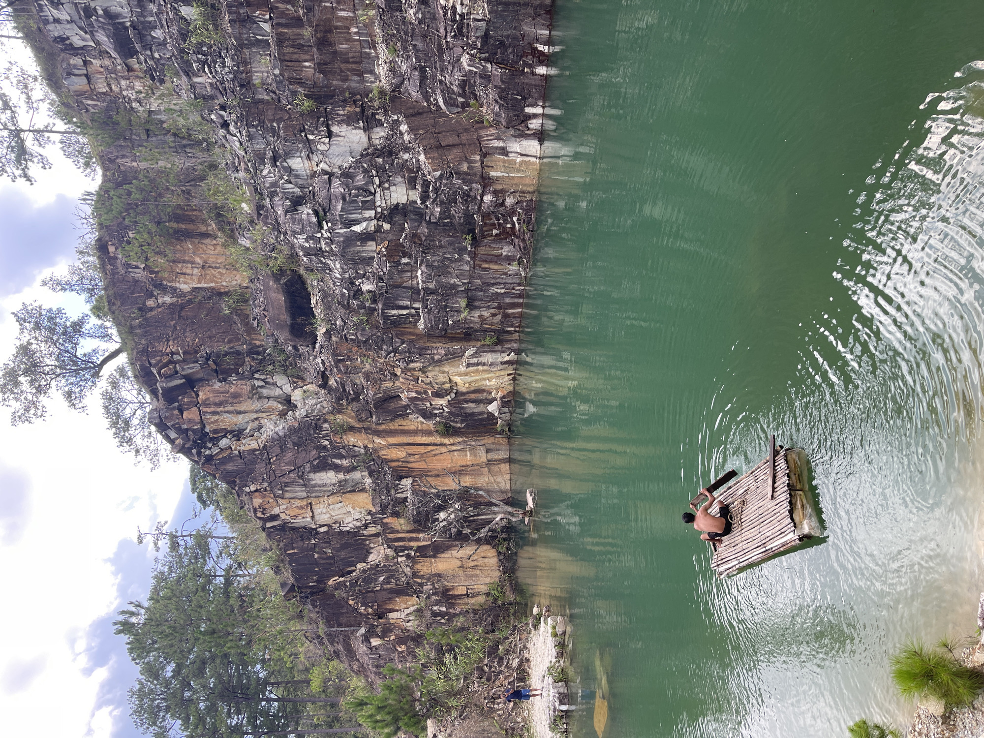 Man paddles bamboo raft in Vietnam quarry waters