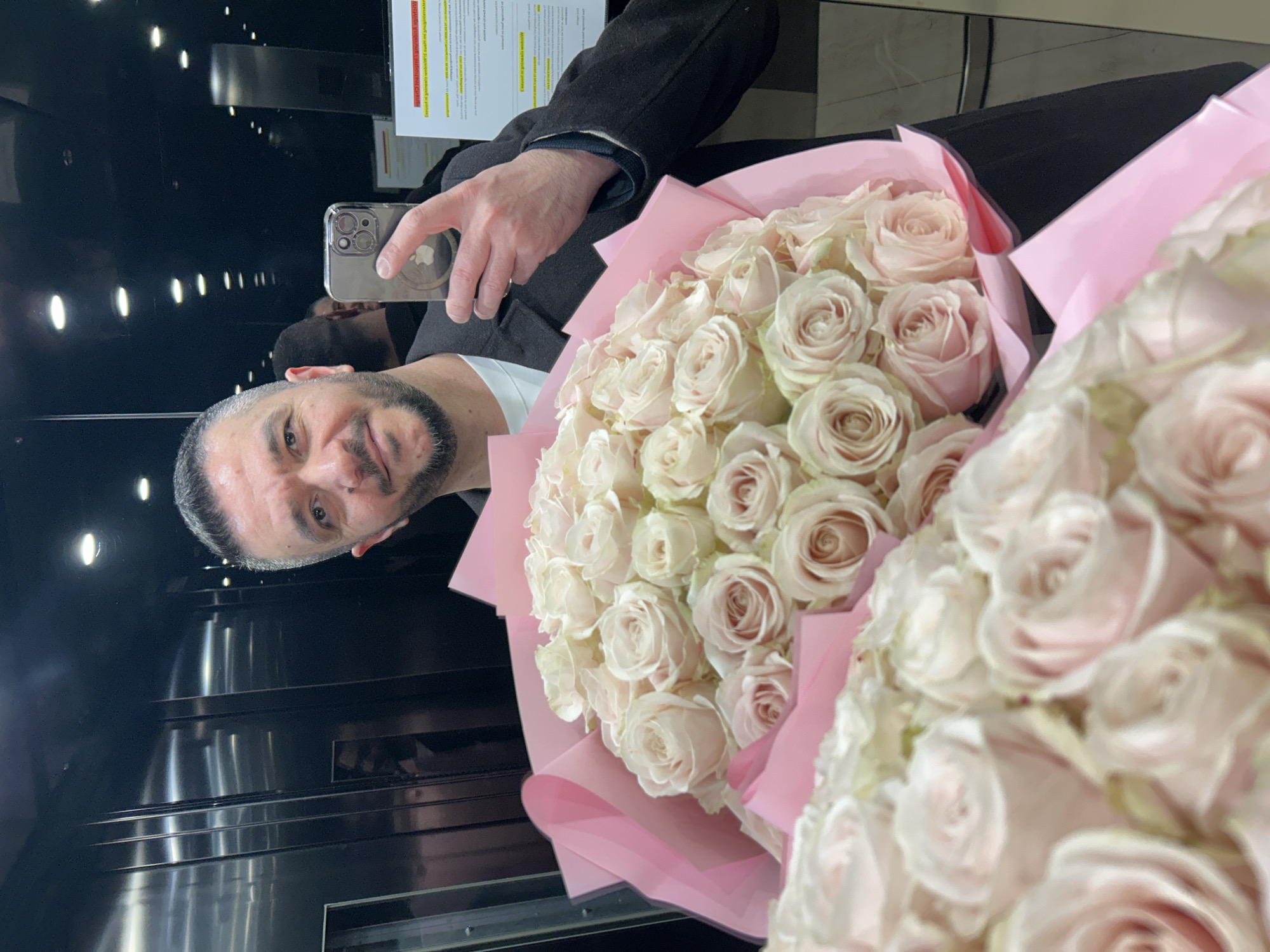 Man takes elevator selfie with pink rose bouquets in Berlin