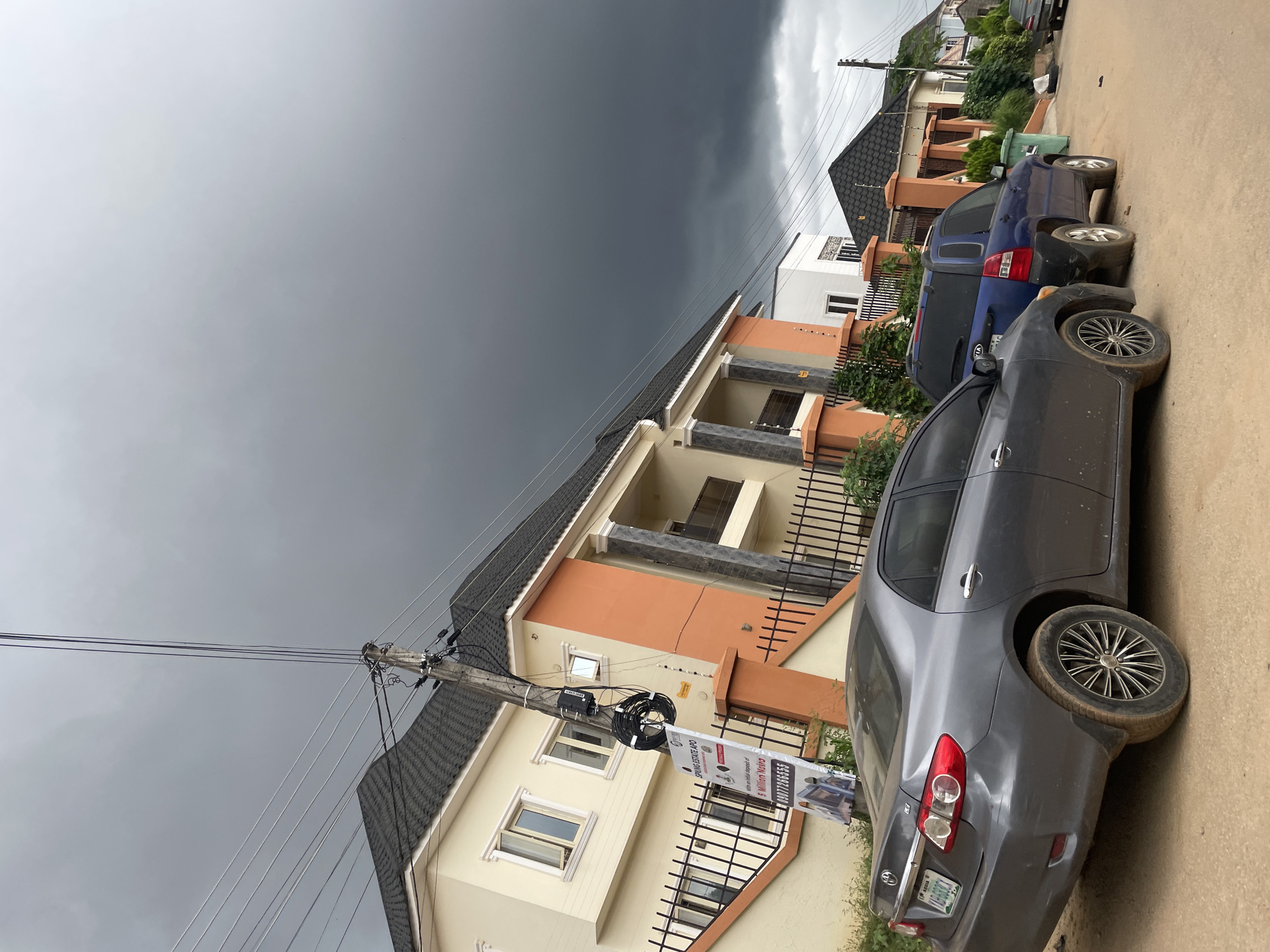 Abuja neighborhood streets under a storm-heavy sky